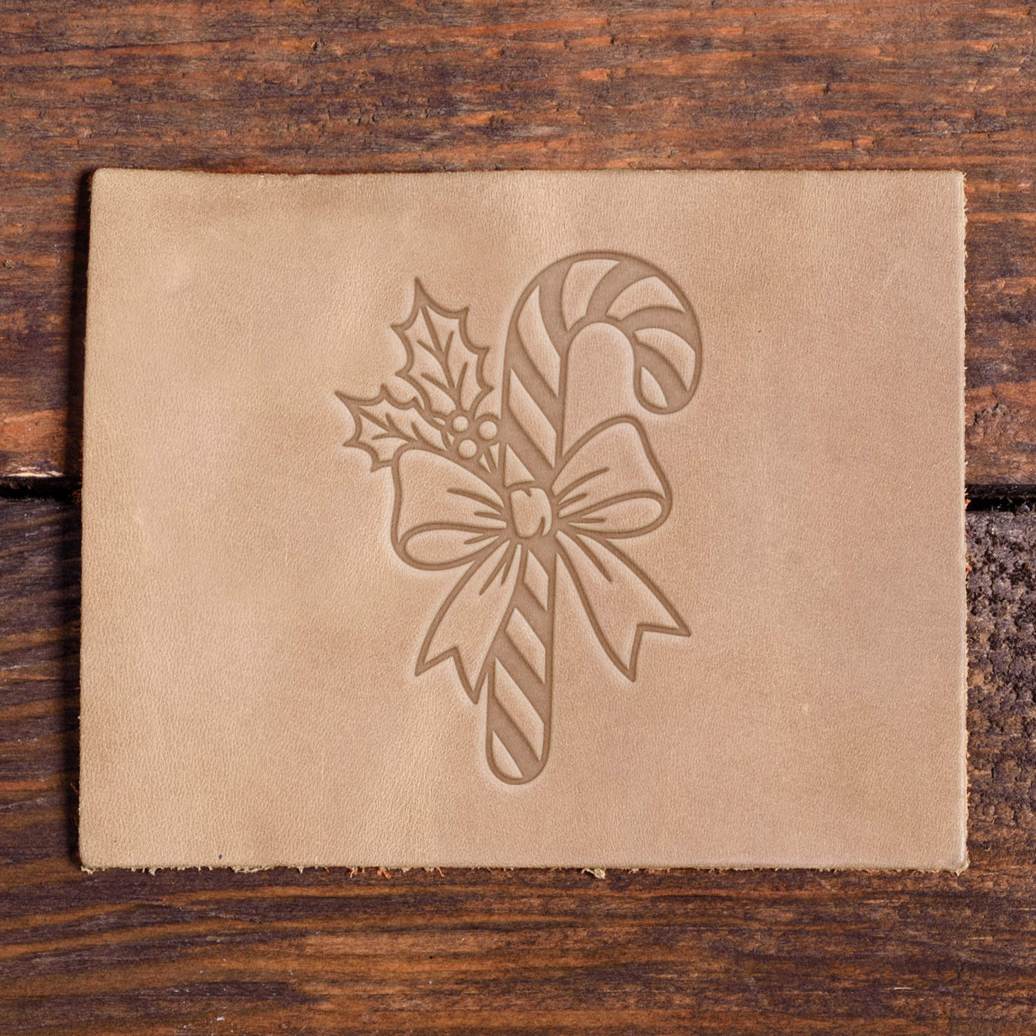 Leather sample with a stamped candy cane and holly design using a Delrin leather stamp, ideal for festive or holiday-themed leather projects.