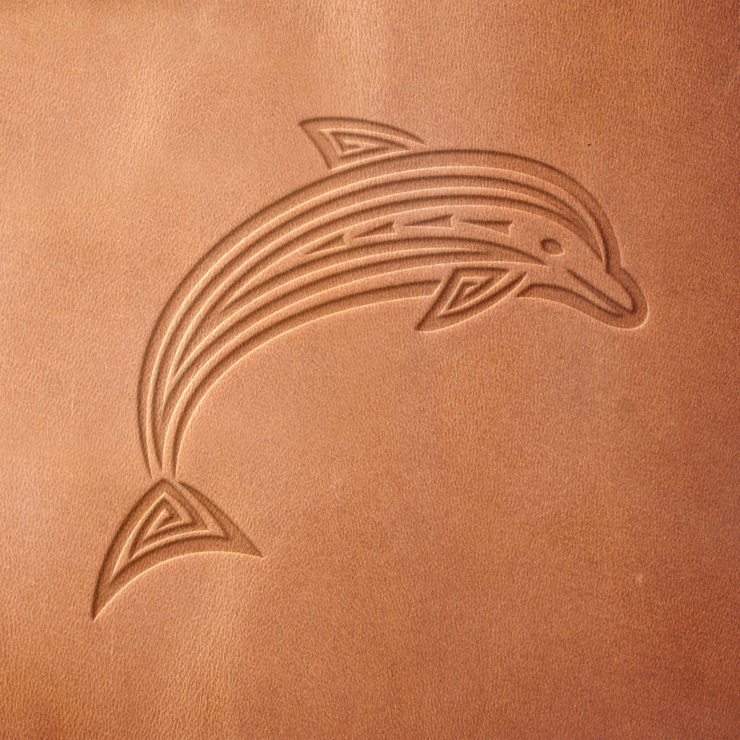 Leather sample with a crisp dolphin stamp impression, featuring bold tribal patterns for a striking ocean-inspired design.
