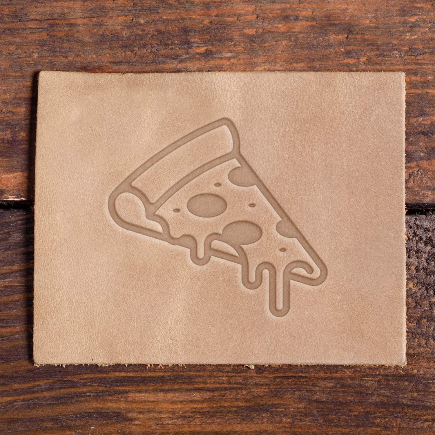 Stamped impression of a dripping pepperoni pizza slice made with a Delrin leather stamp on natural veg-tan leather.