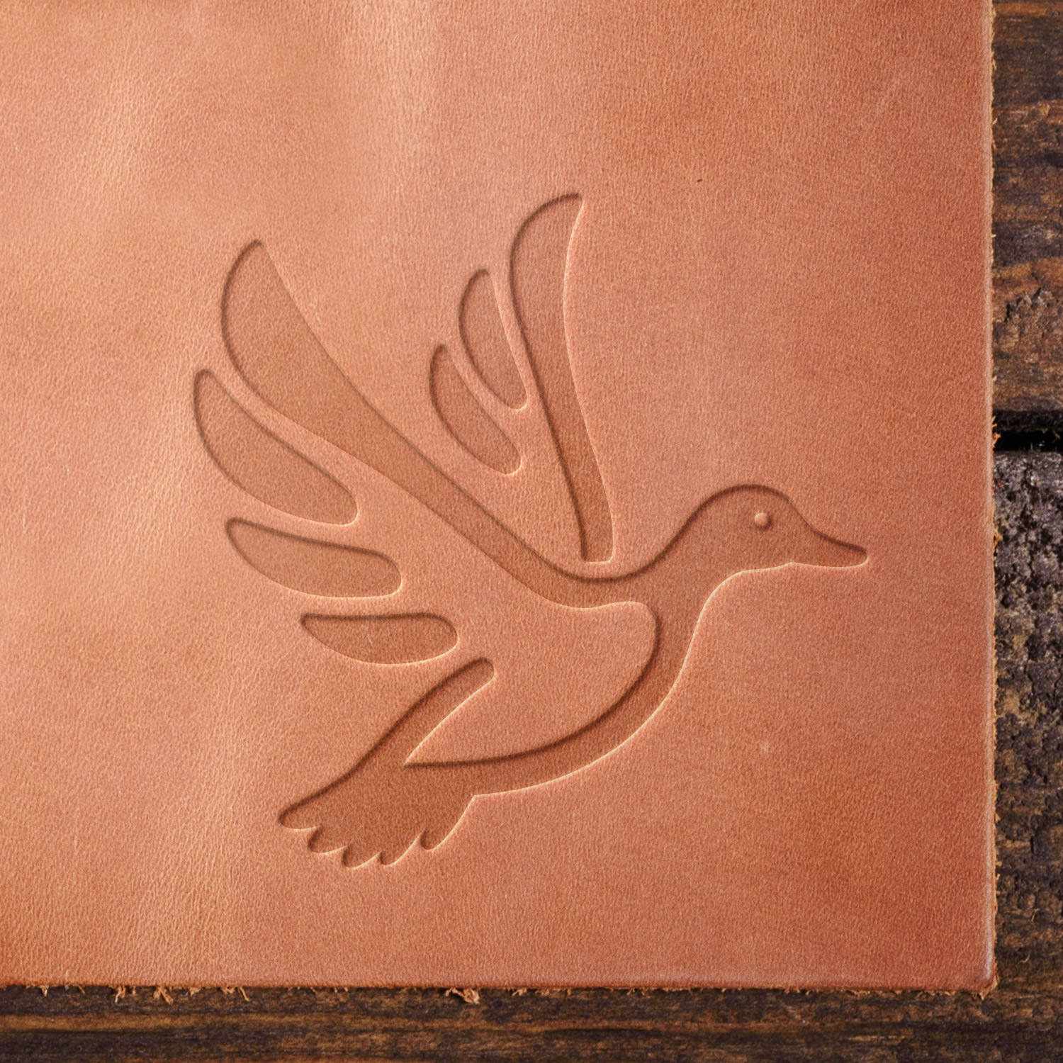 Leather sample showcasing a stamped flying duck design using a delrin leather stamp, highlighting the graceful wing positioning and fluid motion.