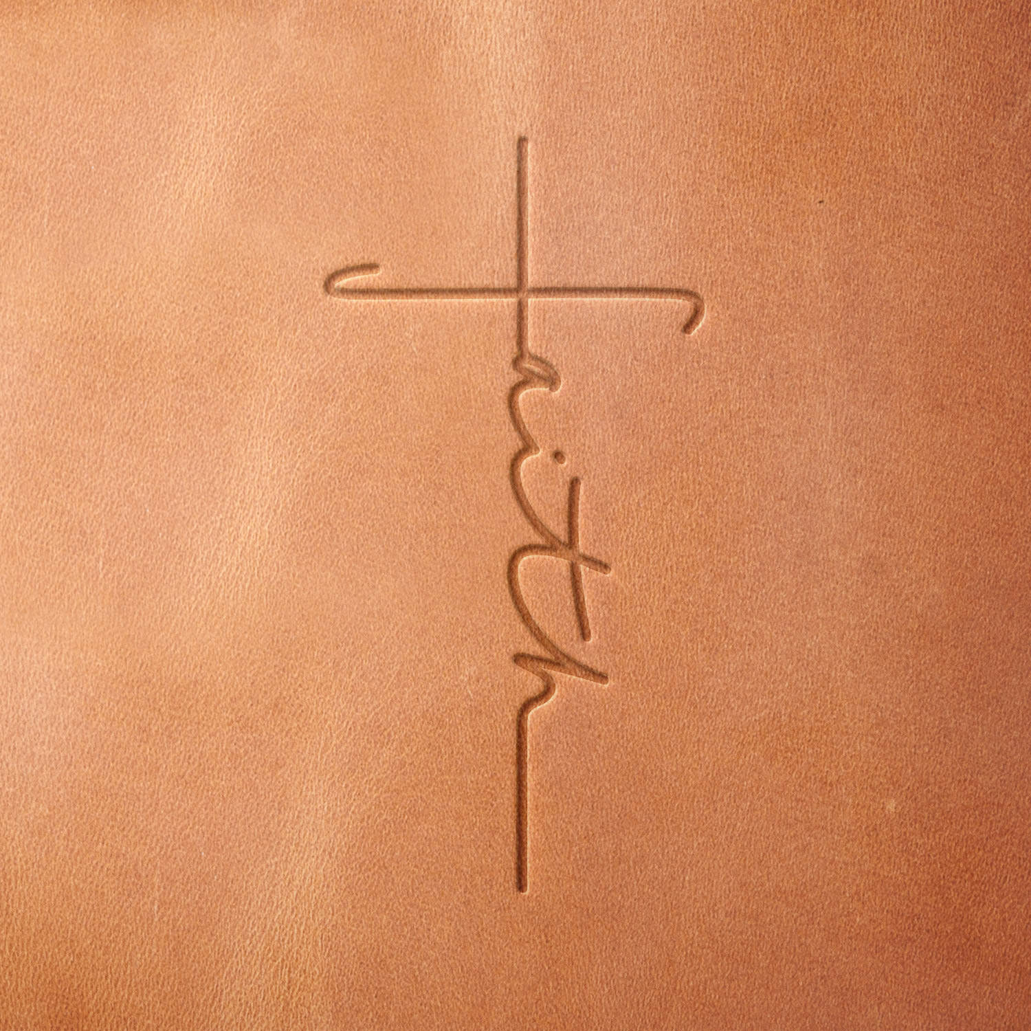 Leather piece stamped with a Delrin leather stamp featuring a script-style “faith” cross design—ideal for Bible covers, gifts, or personal devotional items.
