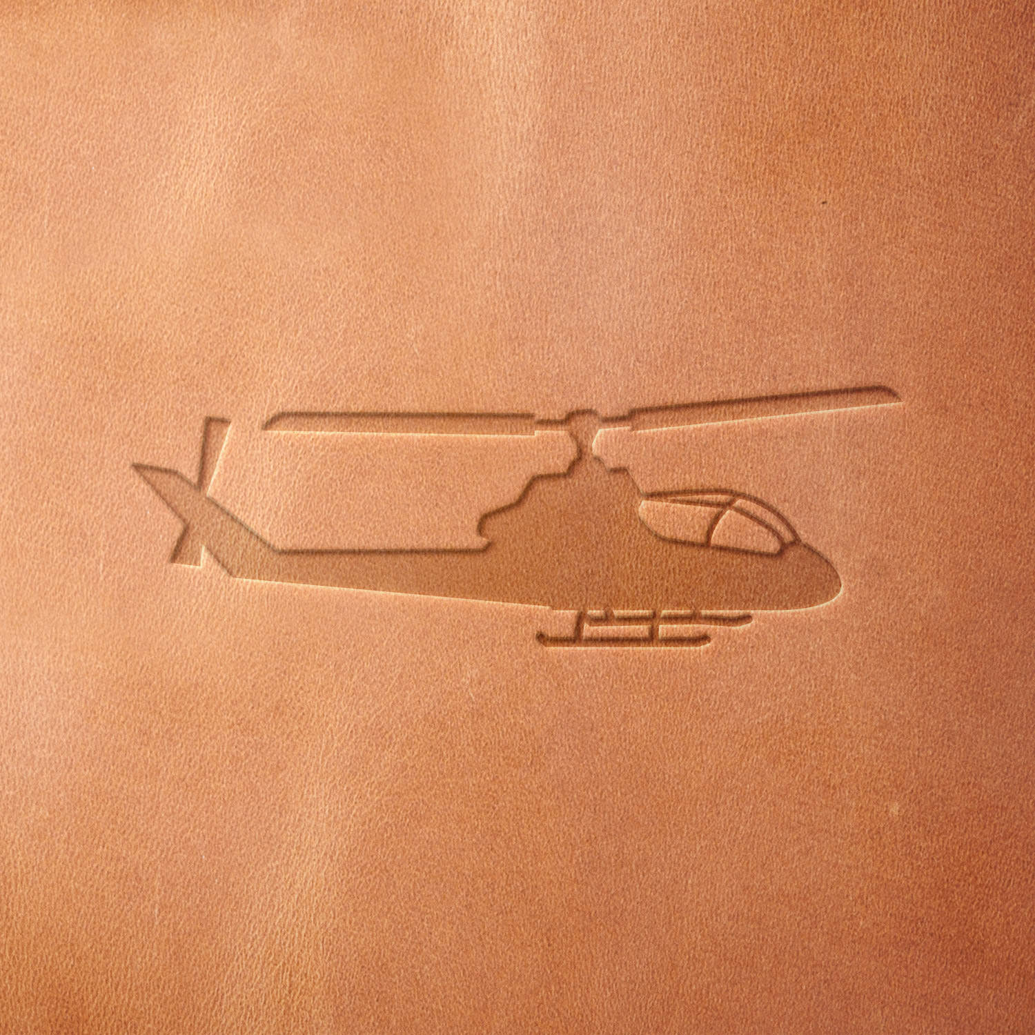 Leather piece stamped with a Delrin leather stamp of a military-style helicopter—great for tactical gear, flight-inspired crafts, or handmade gifts for aviation enthusiasts.