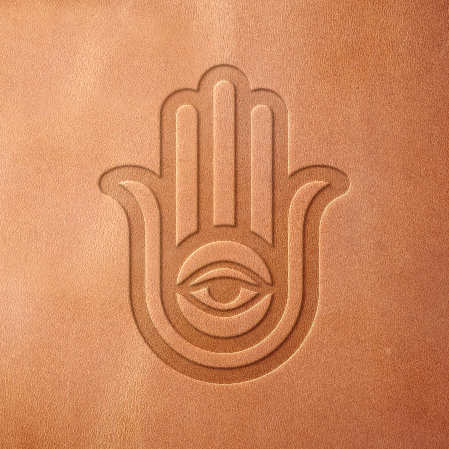 Leather piece stamped with a Delrin leather stamp of a Hamsa hand featuring a central eye—ideal for protective charm-inspired leather goods and spiritual art.