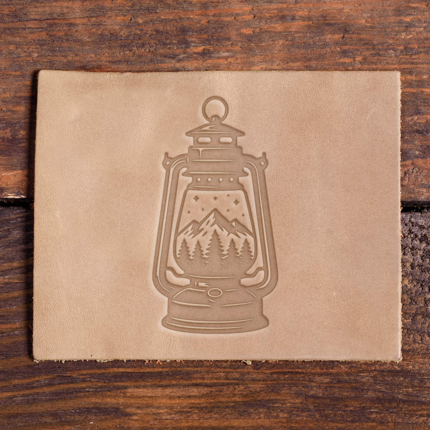 Leather sample with a stamped lantern and mountain scene design using a Delrin leather stamp, ideal for camping or adventure-themed leather projects.