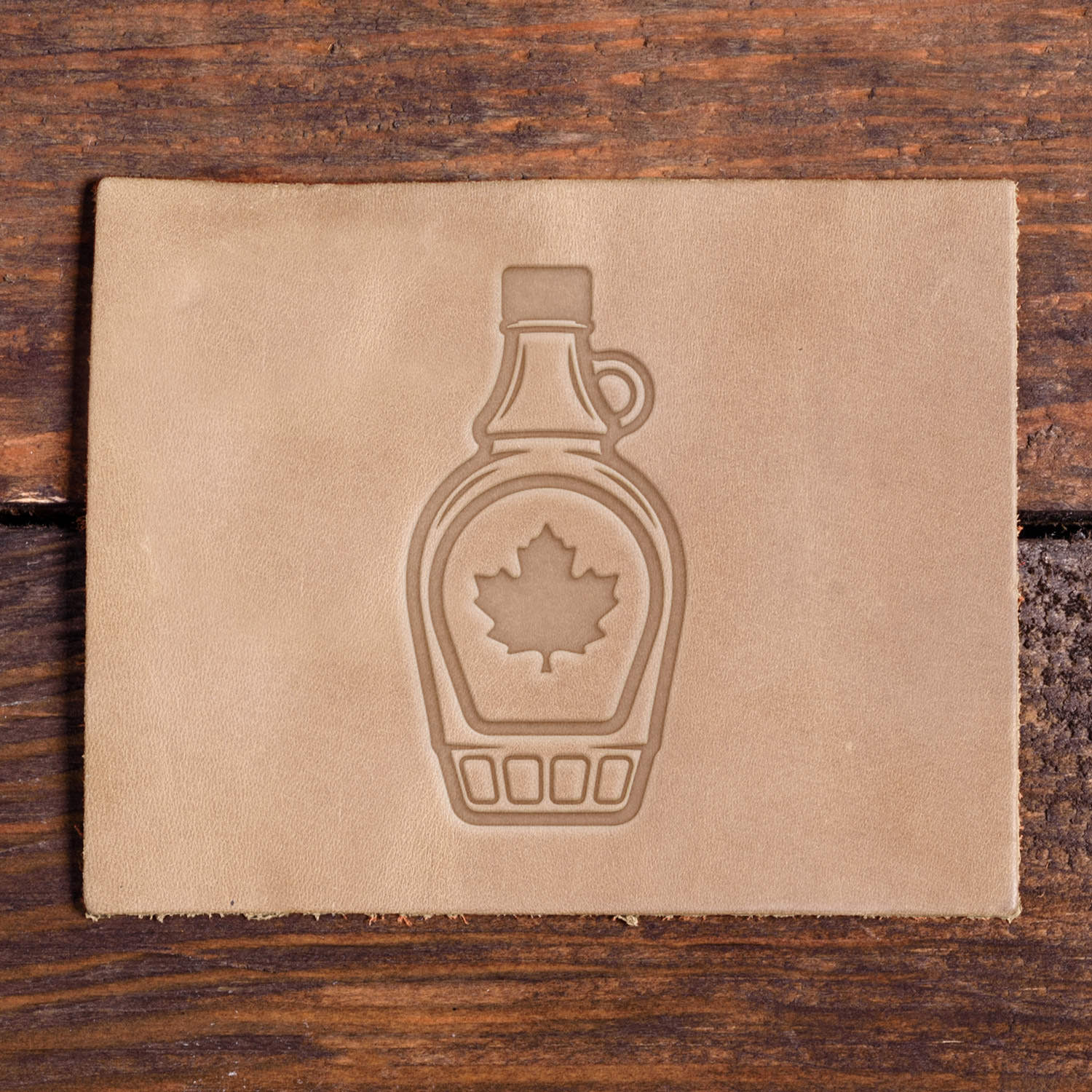 Leather sample with a stamped maple syrup bottle design using a Delrin leather stamp, great for Canada-inspired or rustic leather projects.