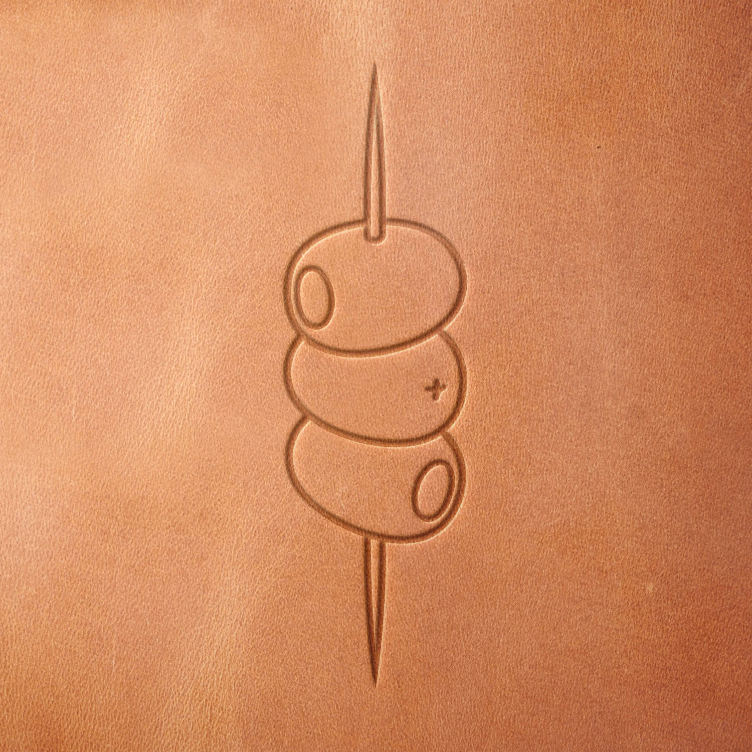 Leather piece stamped with a Delrin leather stamp showing three skewered olives—perfect for mixology fans, handmade bar sets, or drink-themed craft projects.
