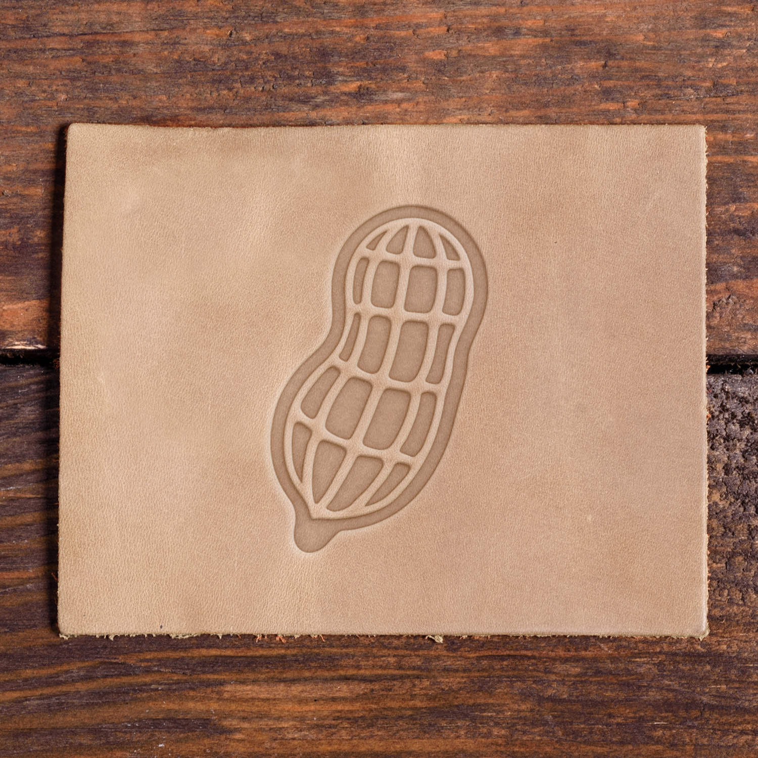 Leather piece stamped with a Delrin leather stamp design of a peanut in its shell, featuring bold lines and a classic shape.