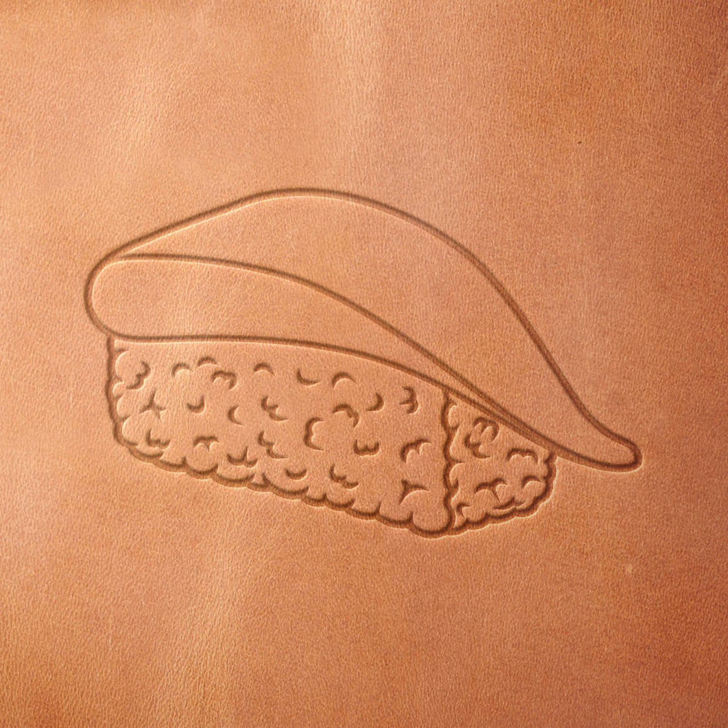 Leather piece stamped with a Delrin leather stamp of simple fish nigiri—perfect for culinary leathercraft, chef gear personalization, or sushi-inspired creations.