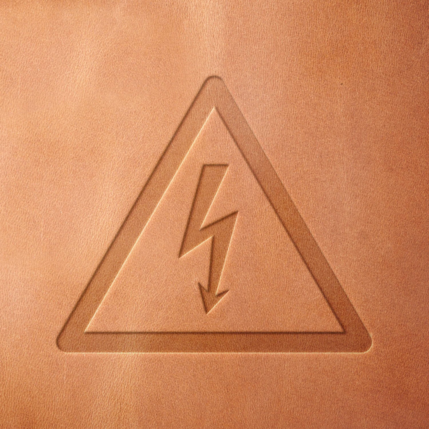 Leather piece stamped with a Delrin leather stamp of a high voltage warning icon—great for edgy, tech-inspired leather goods or themed utility items.