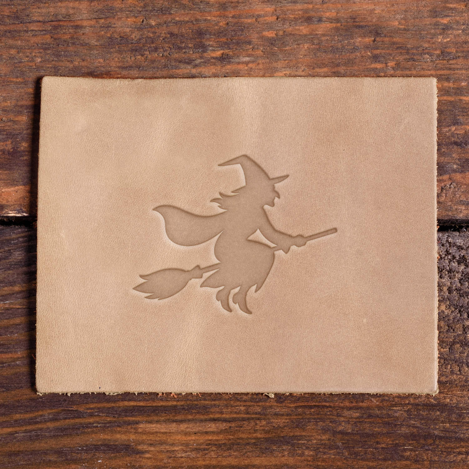 Leather piece stamped with a Delrin leather stamp design of a witch on a broomstick, perfect for Halloween and spooky-themed leather projects.