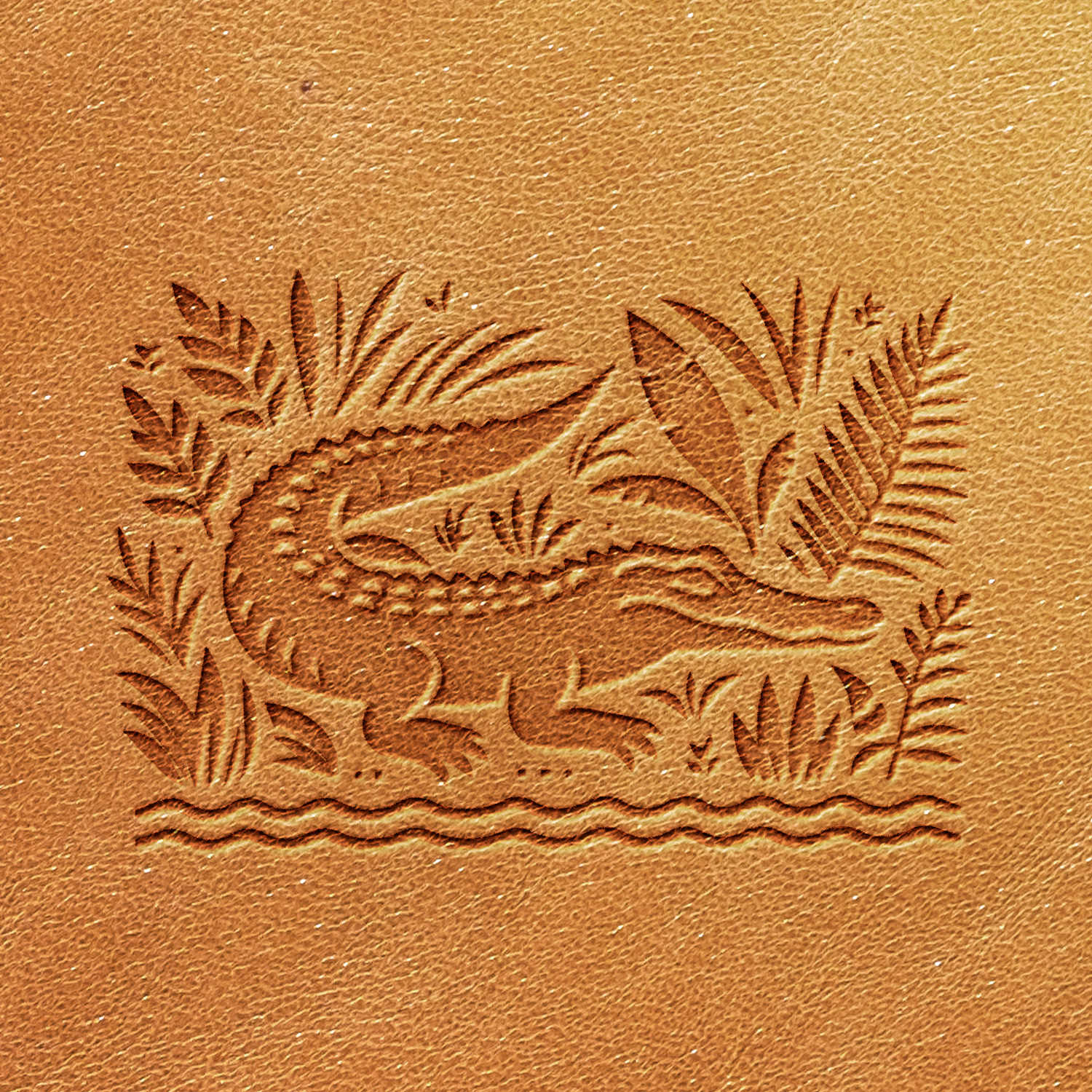 The Alligator Delrin Leather Stamp showcases a detailed textured imprint of a crocodile amidst tropical plants and water on a light brown leather surface, featuring intricate lines and patterns to depict the animal and its surroundings.