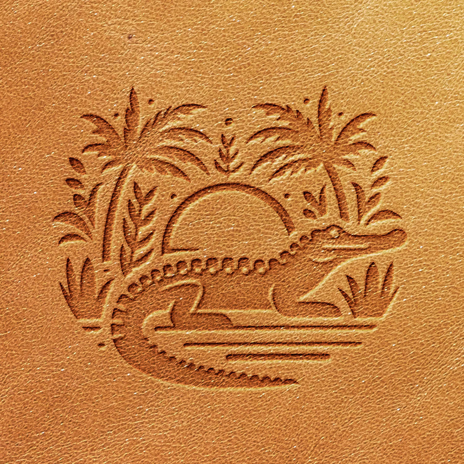 The Alligator Delrin Leather Stamp features a detailed embossed image on textured brown leather, depicting an alligator with the sun setting in the background, flanked by palm trees and reeds. This design artfully combines natural elements in a stylized and artistic manner.