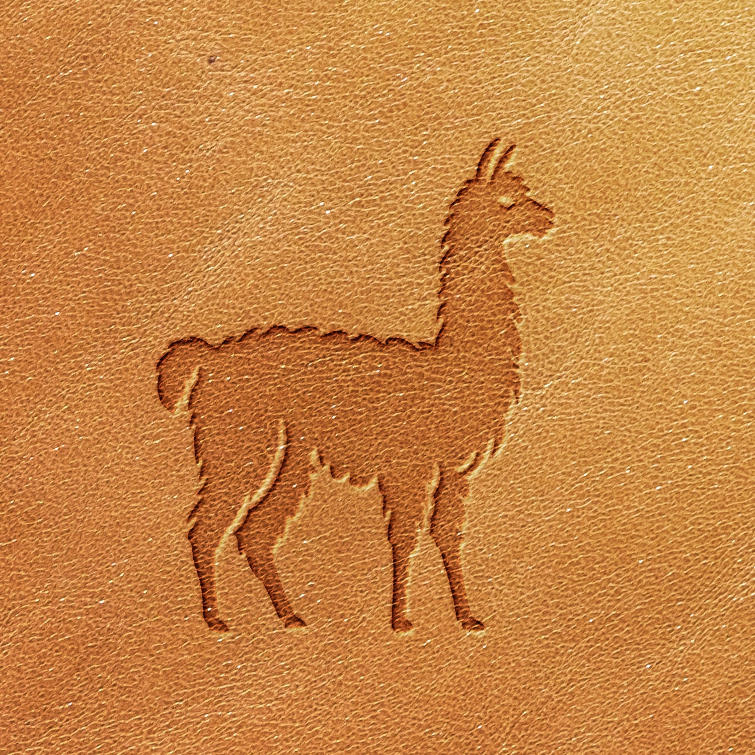 The Alpaca Delrin Leather Stamp embosses a standing silhouette of a llama, facing right, onto tan leather. The texture and grain of the leather are visible, adding a tactile quality to the image.