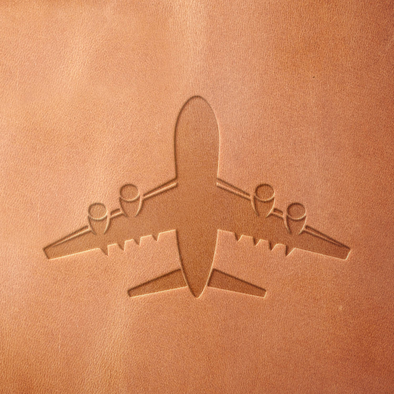 Leather piece stamped with a Delrin leather stamp of an overhead jet design—ideal for luggage tags, pilot logbook covers, or aviation enthusiast gear.