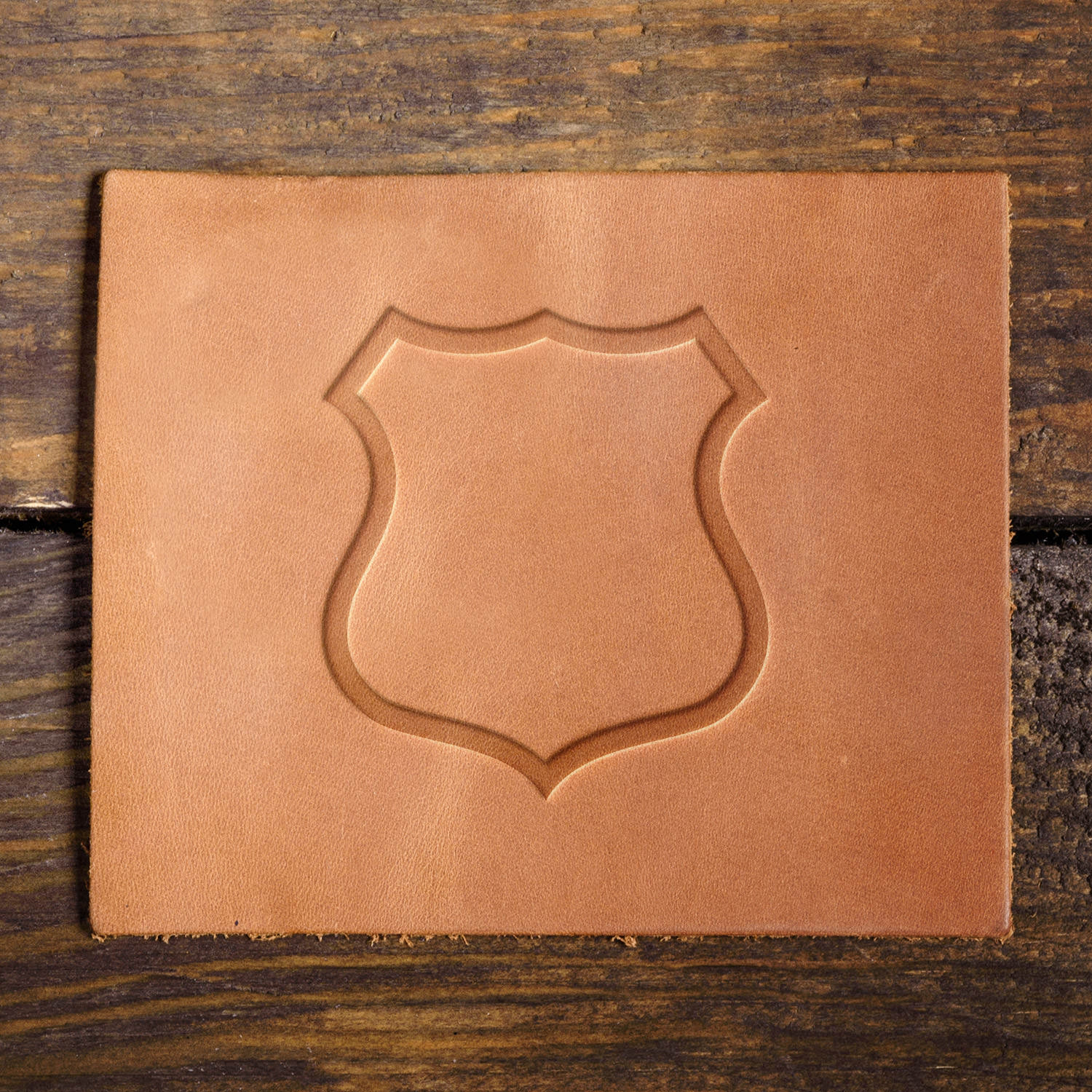 Leather sample showcasing a police shield outline stamped with a Delrin leather stamp, creating a crisp and professional emblem shape.