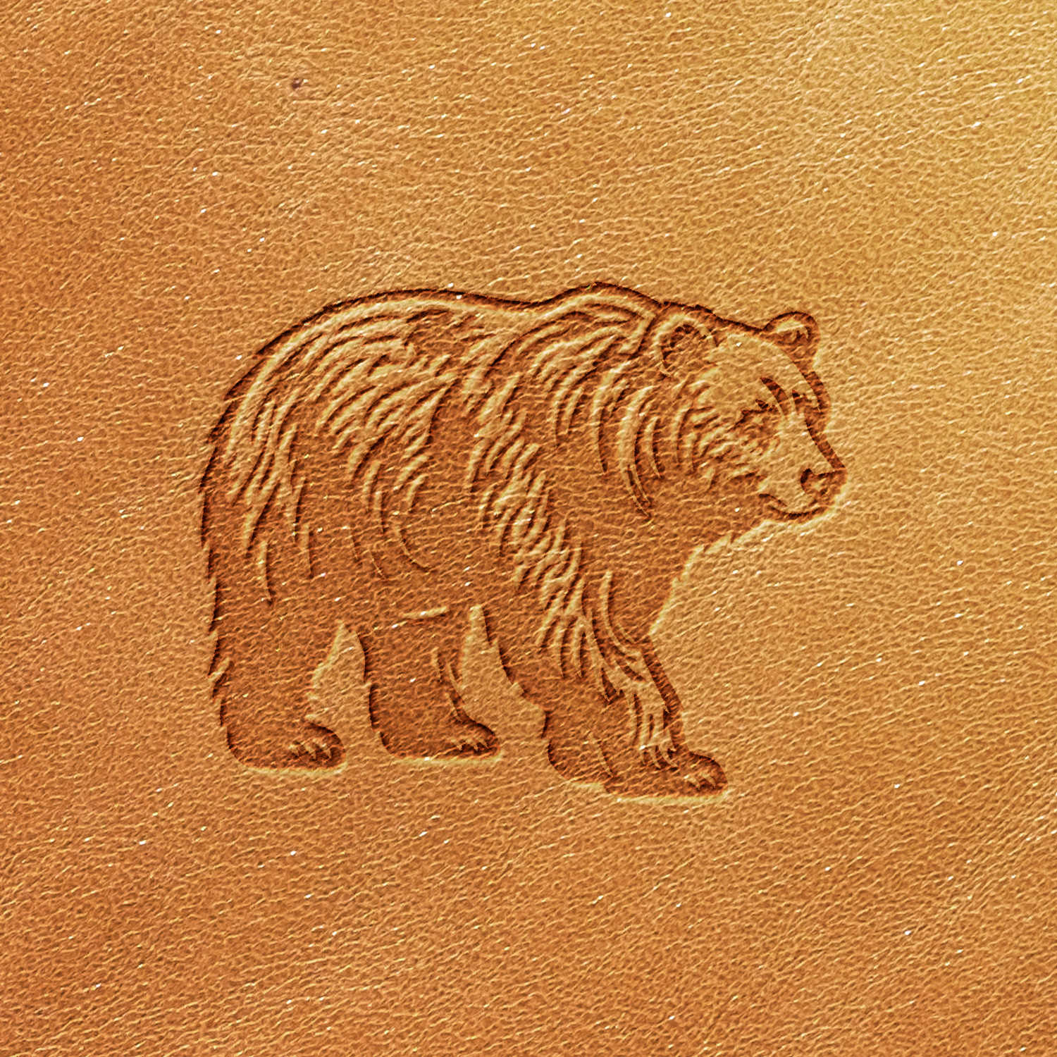 The Bear Delrin Leather Stamp creates an embossed image of a bear on the brown leather, depicting it standing on all fours and facing right. The leather texture is clearly visible, with the bear image appearing raised from the surface.