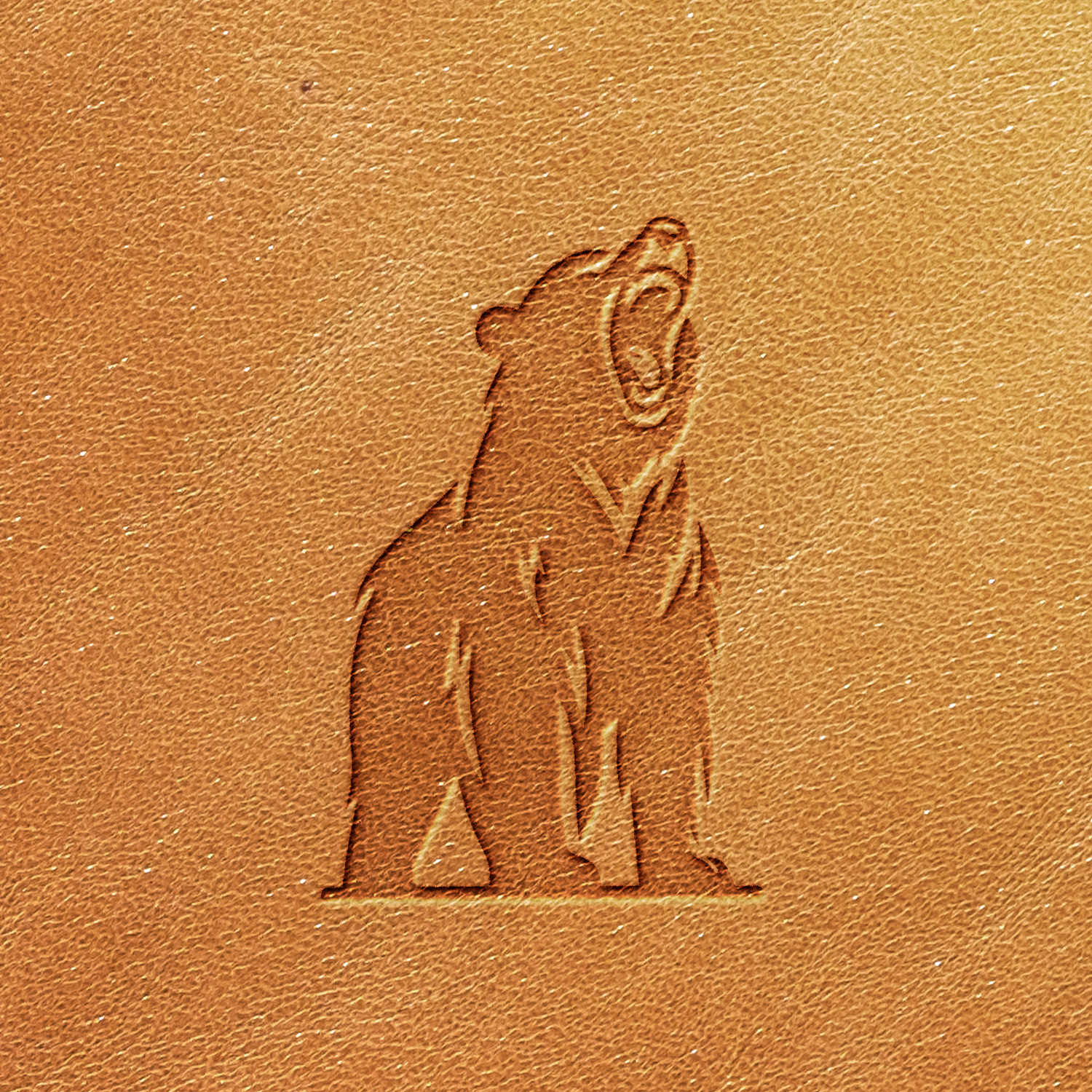 The Growling Bear Delrin Leather Stamp features the design of a roaring bear standing on its hind legs, mouth open and facing slightly upwards. The stamp leaves a simple, clean-lined impression on light brown leather material.