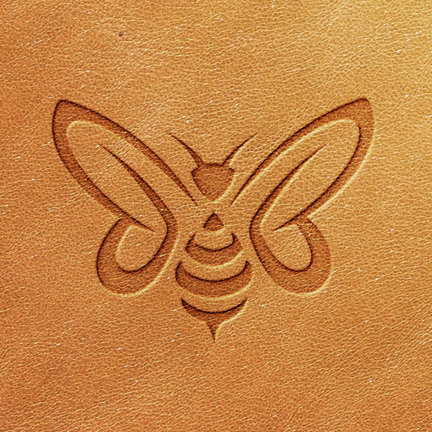 An image created using the Bee Delrin Leather Stamp on a tan leather surface shows a stylized bee in a symmetrical design, with the bee's wings and body marked in simple, curved lines. The leather embossing highlights the smooth texture of the material.