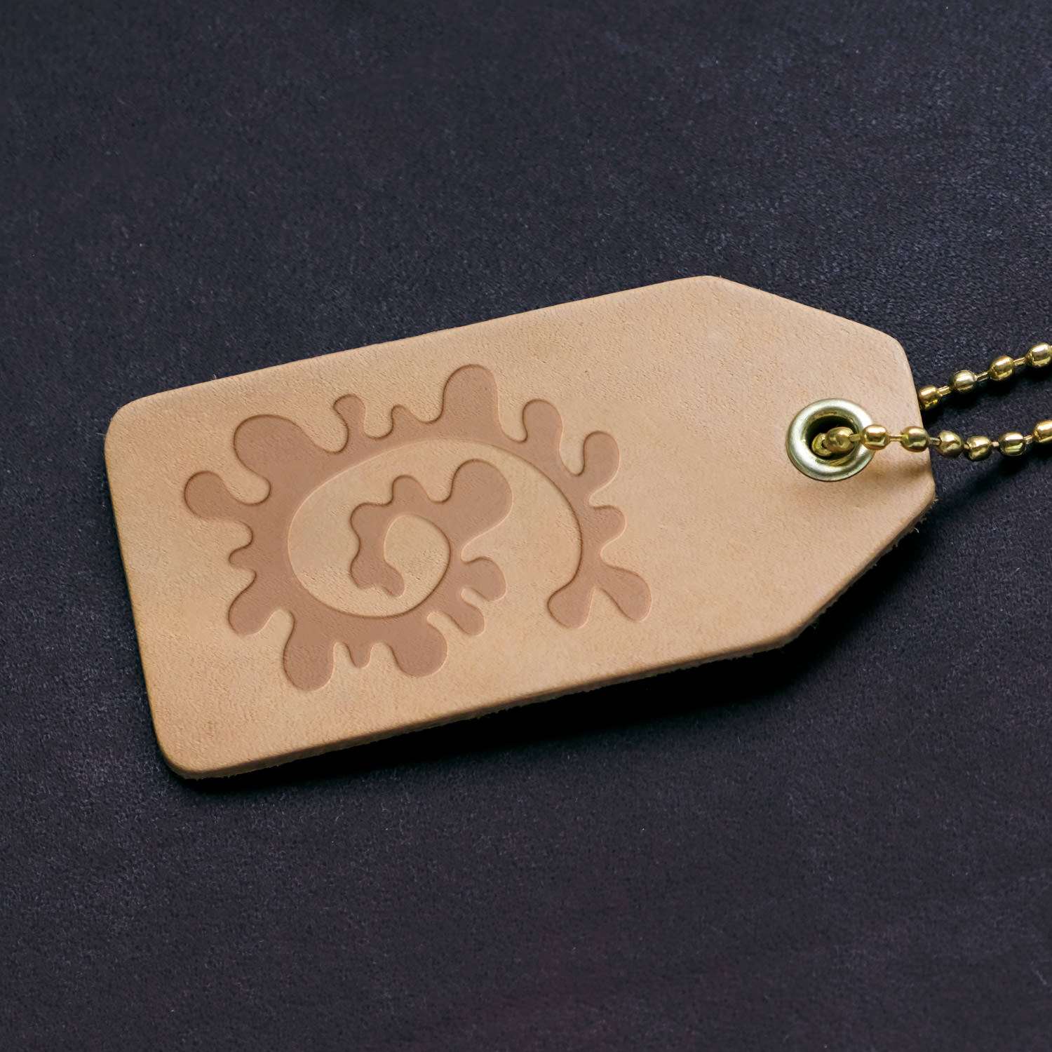 Keychain with abstract spiral coral-inspired pattern leather stamp imprint, showcasing a dynamic and swirling design on leather