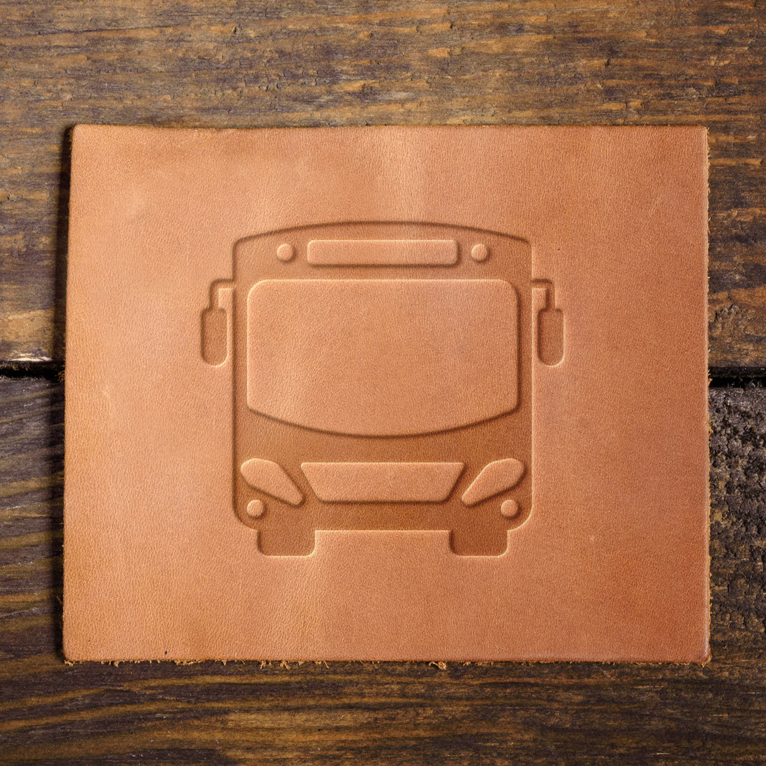 Leather sample showcasing a bus design, stamped with a Delrin leather stamp, symbolizing public transit, travel, and city transportation.