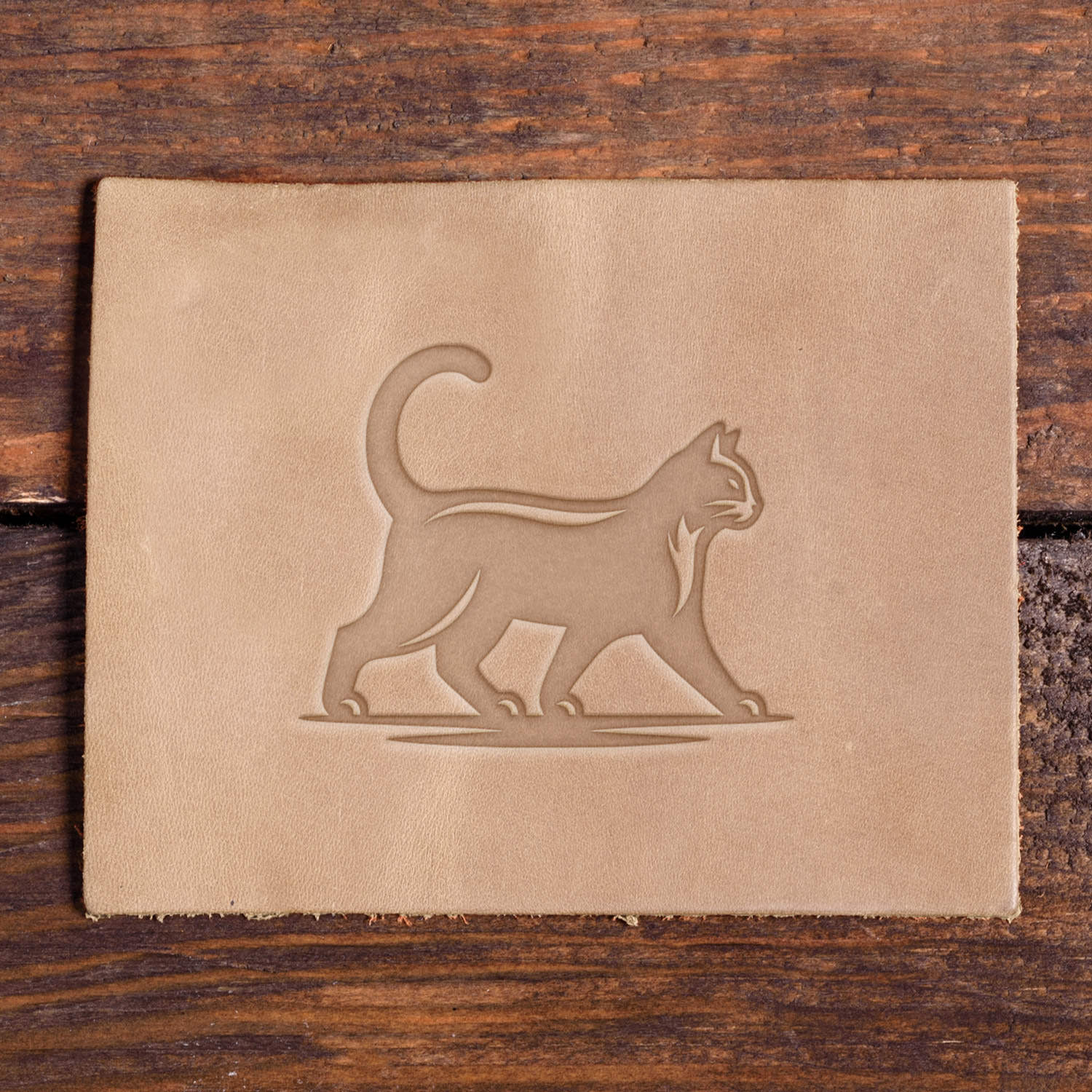 Leather piece stamped with a Delrin leather stamp design of a cat striding forward with its tail raised and smooth, clean detailing.