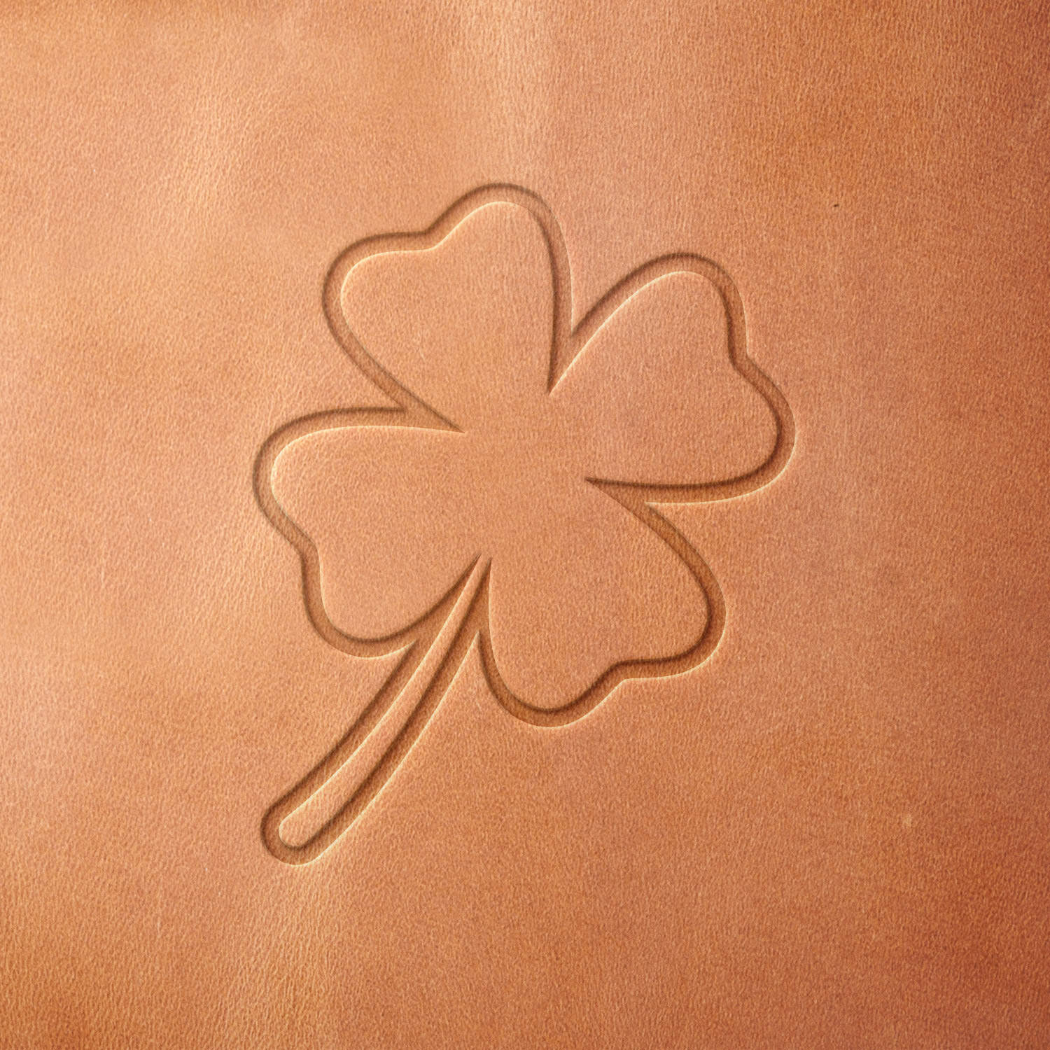 Leather sample showcasing a stamped four-leaf clover design using a delrin leather stamp, emphasizing its lucky symbolism and clean outline.