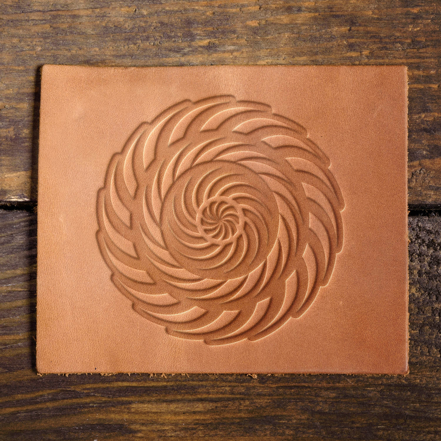 Leather sample with a stamped spiral vortex design, adding a mesmerizing and dynamic element to leatherwork.