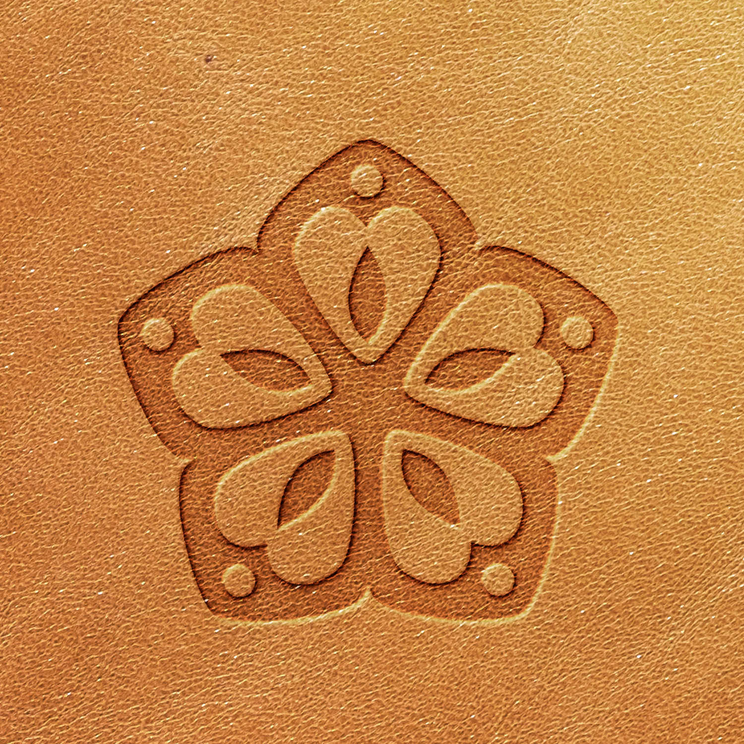 A close-up shot showcasing the detailed embossing created by the Flower Delrin Leather Stamp on a tan leather surface. The design prominently features a five-petal flower with intricate detailing and small circular accents near the petal tips, vividly displaying both the texture of the leather and the depth of embossing.