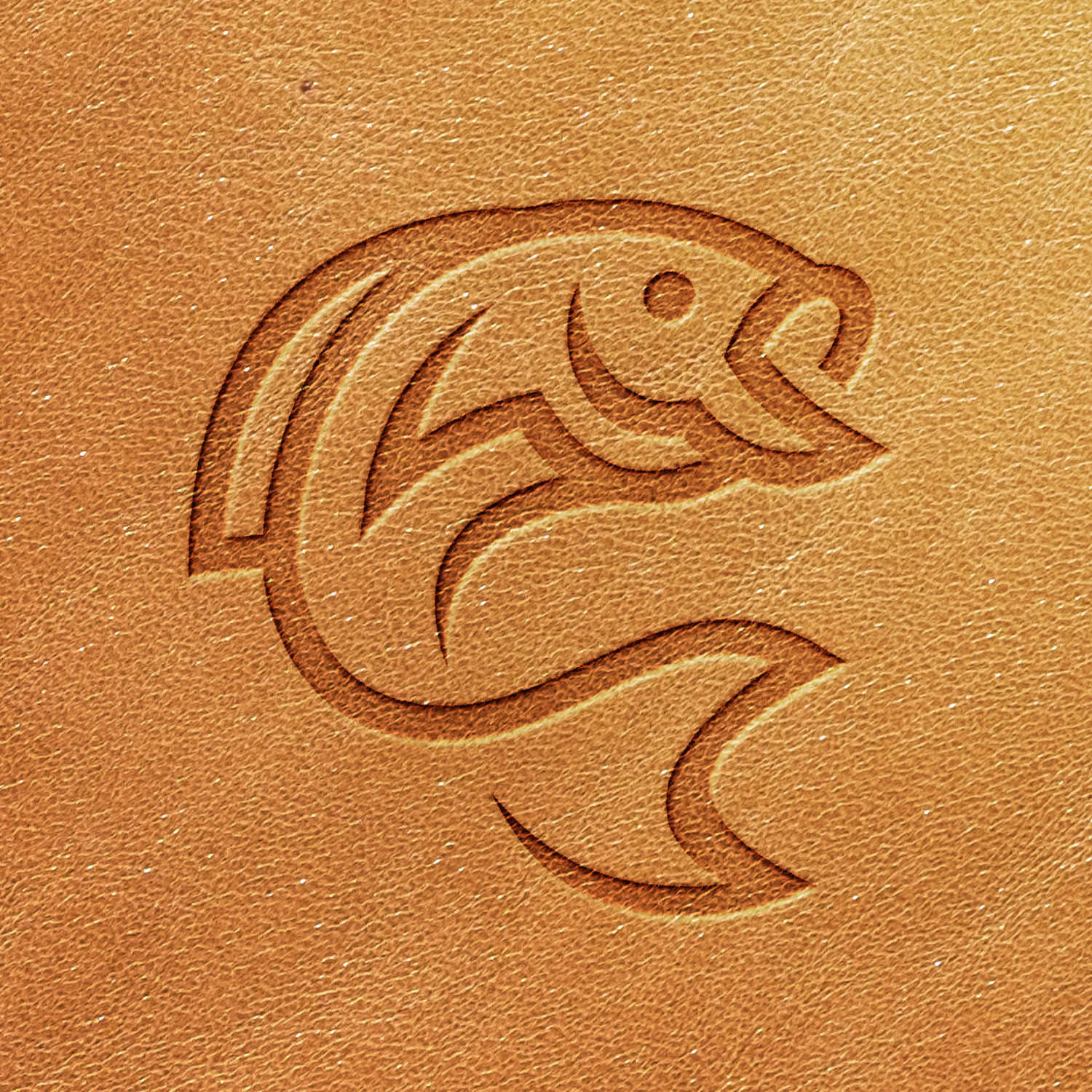 A Fish Delrin Leather Stamp features a stylized design of a fish embossed on a tan leather surface. The fish is depicted in a curved, simplified outline with minimal details.