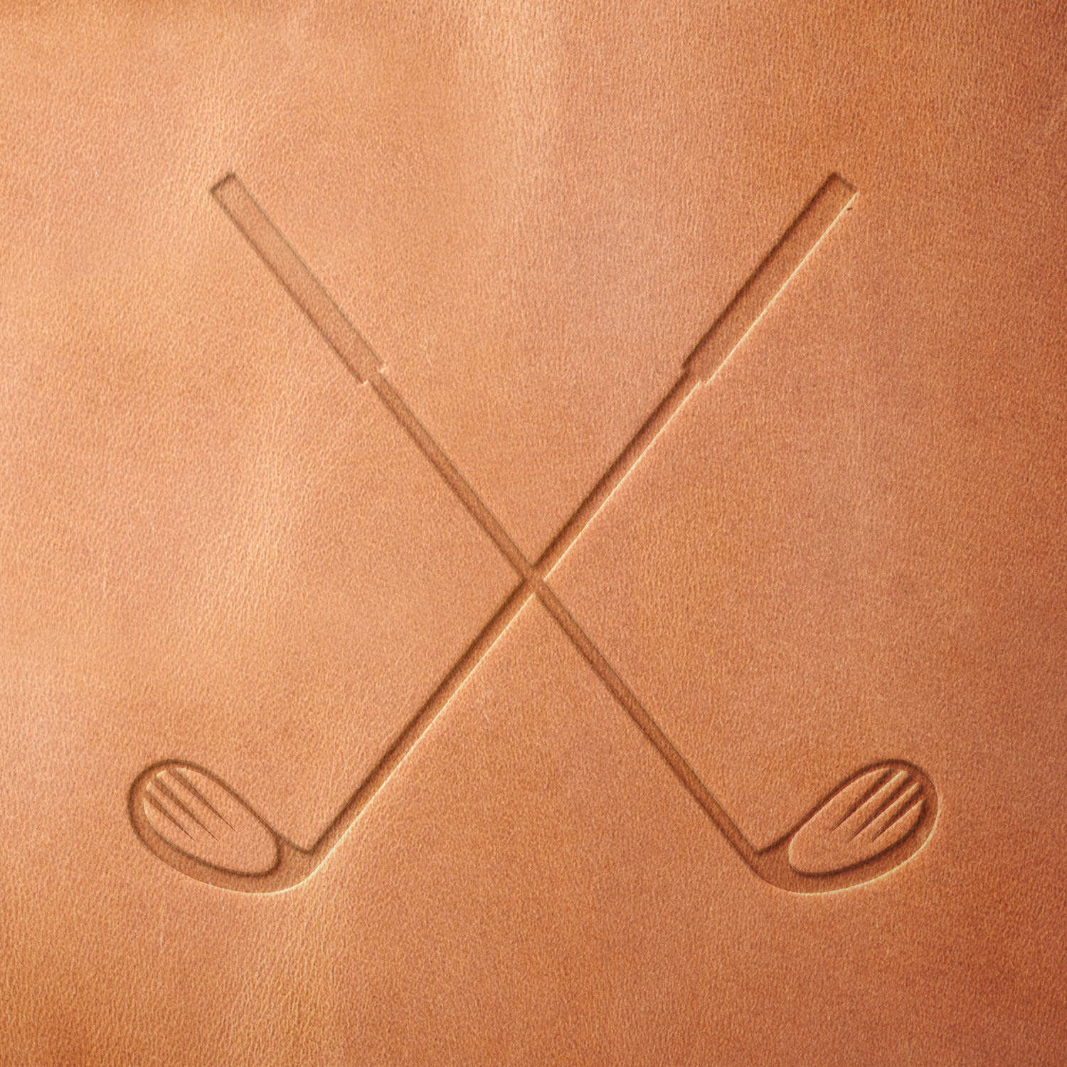 Leather sample showcasing a stamped crossed golf clubs design using a delrin leather stamp, highlighting the clubs’ clean lines and balanced arrangement.