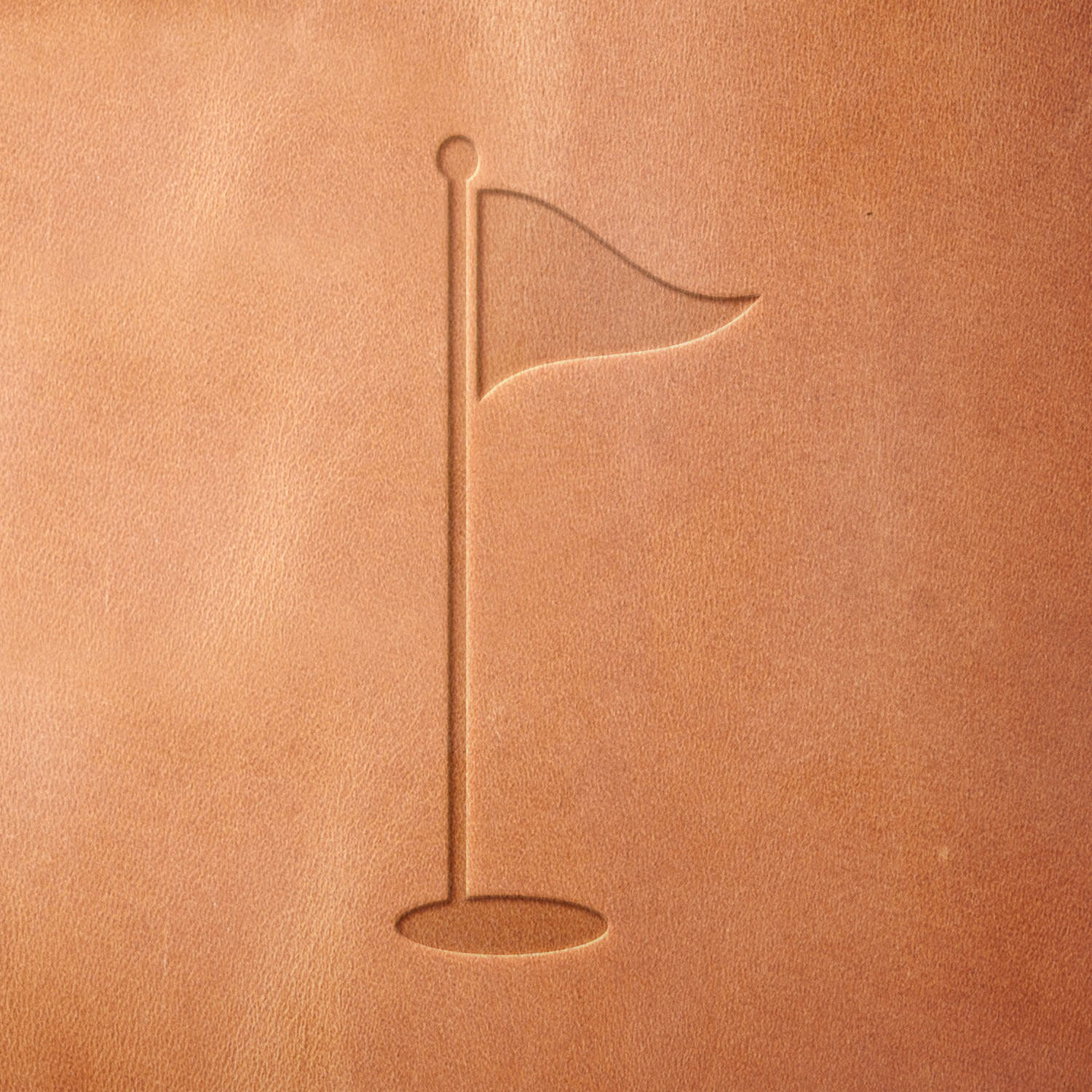 Leather sample showcasing a stamped flag on a stand design using a delrin leather stamp, highlighting the clean silhouette and subtle wave of the flag.