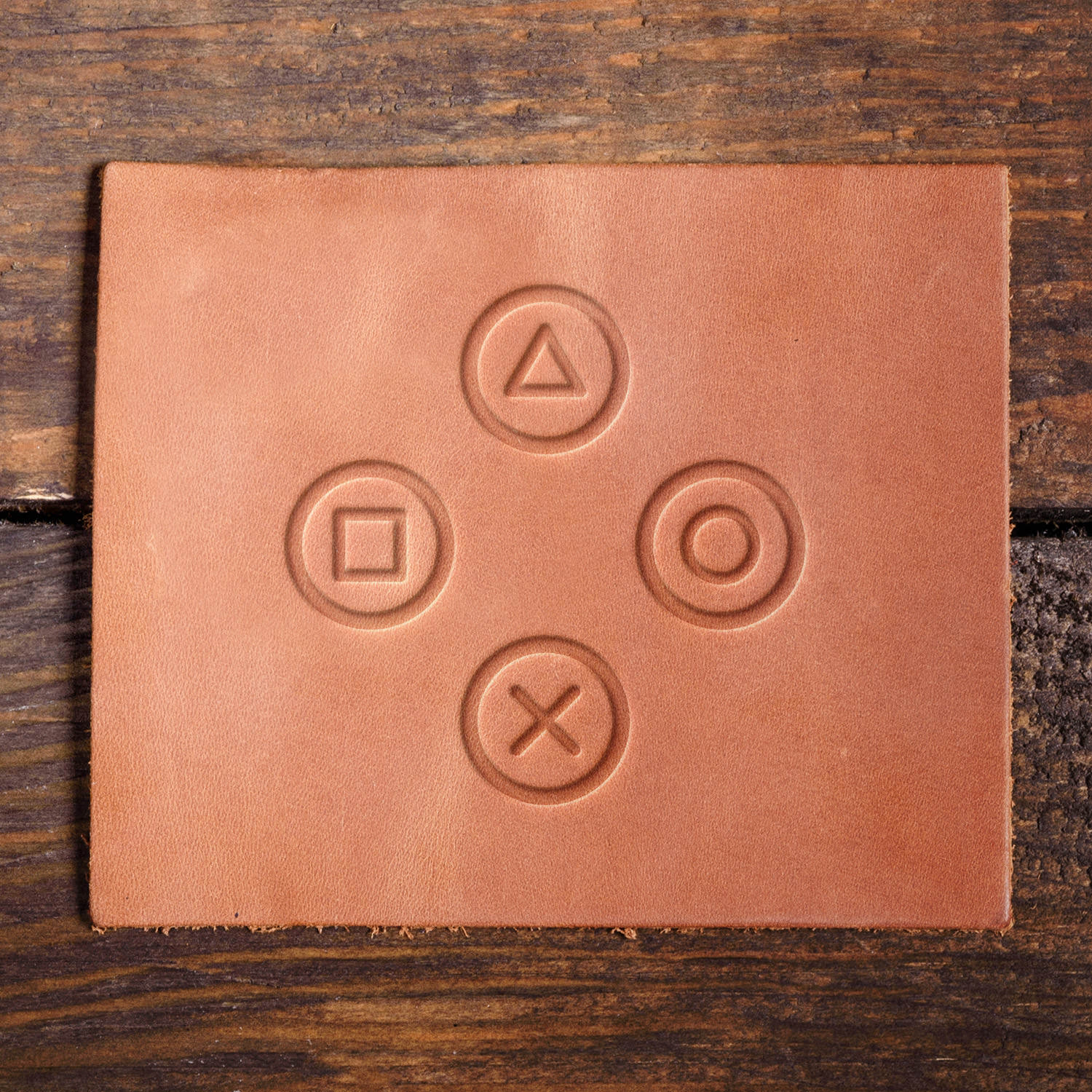 Leather sample with a crisp PlayStation-style game controller button layout stamp impression from a Delrin leather stamp, ideal for creating high-quality gaming and retro-themed leathercraft projects.