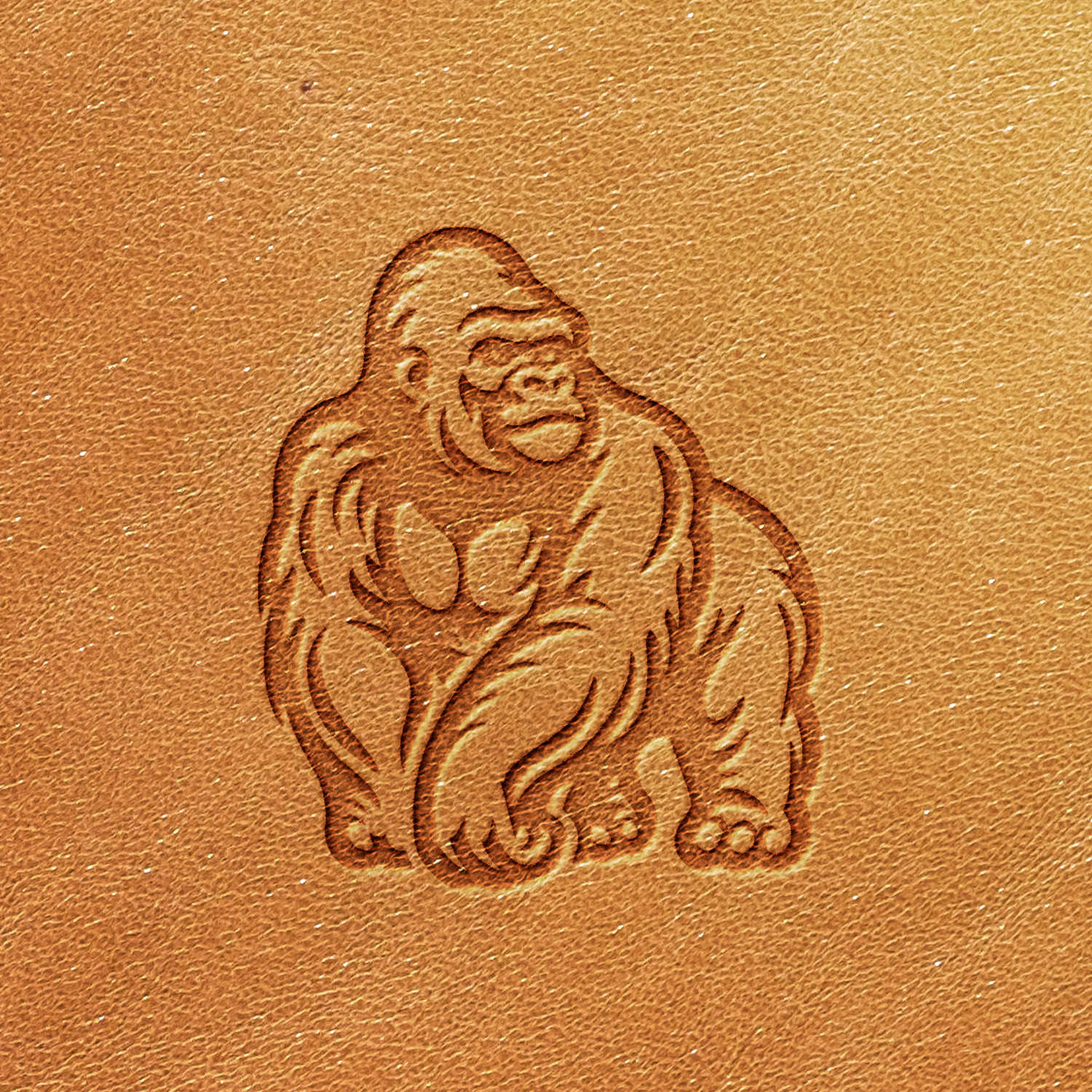 Introducing the Gorilla Delrin Leather Stamp: an exquisitely embossed image of a gorilla on a light brown leather surface. The design portrays the gorilla in a sitting position, showcasing detailed fur and muscular features.