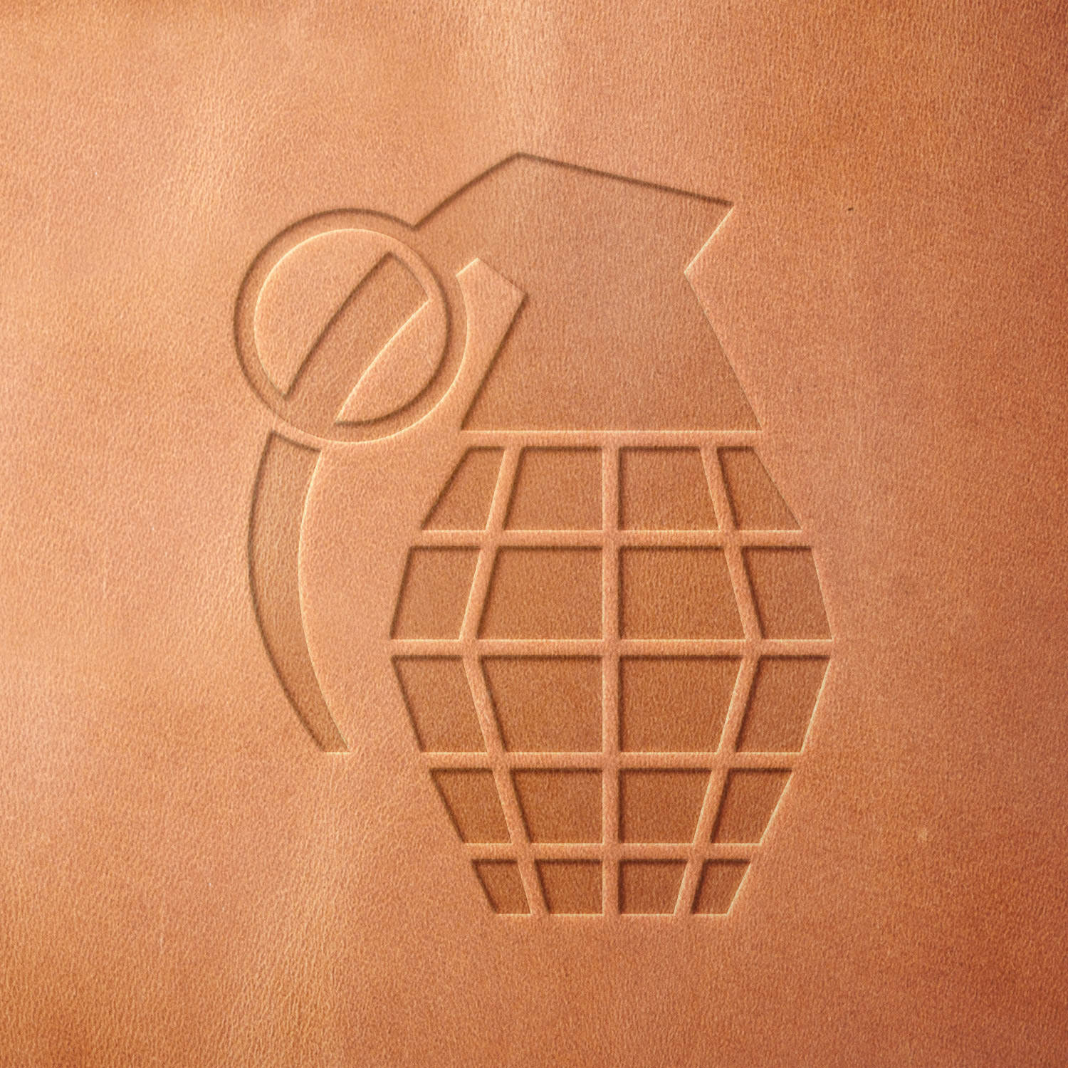 Leather sample showcasing a stamped grenade design using a delrin leather stamp, emphasizing the segmented pattern and bold outline.