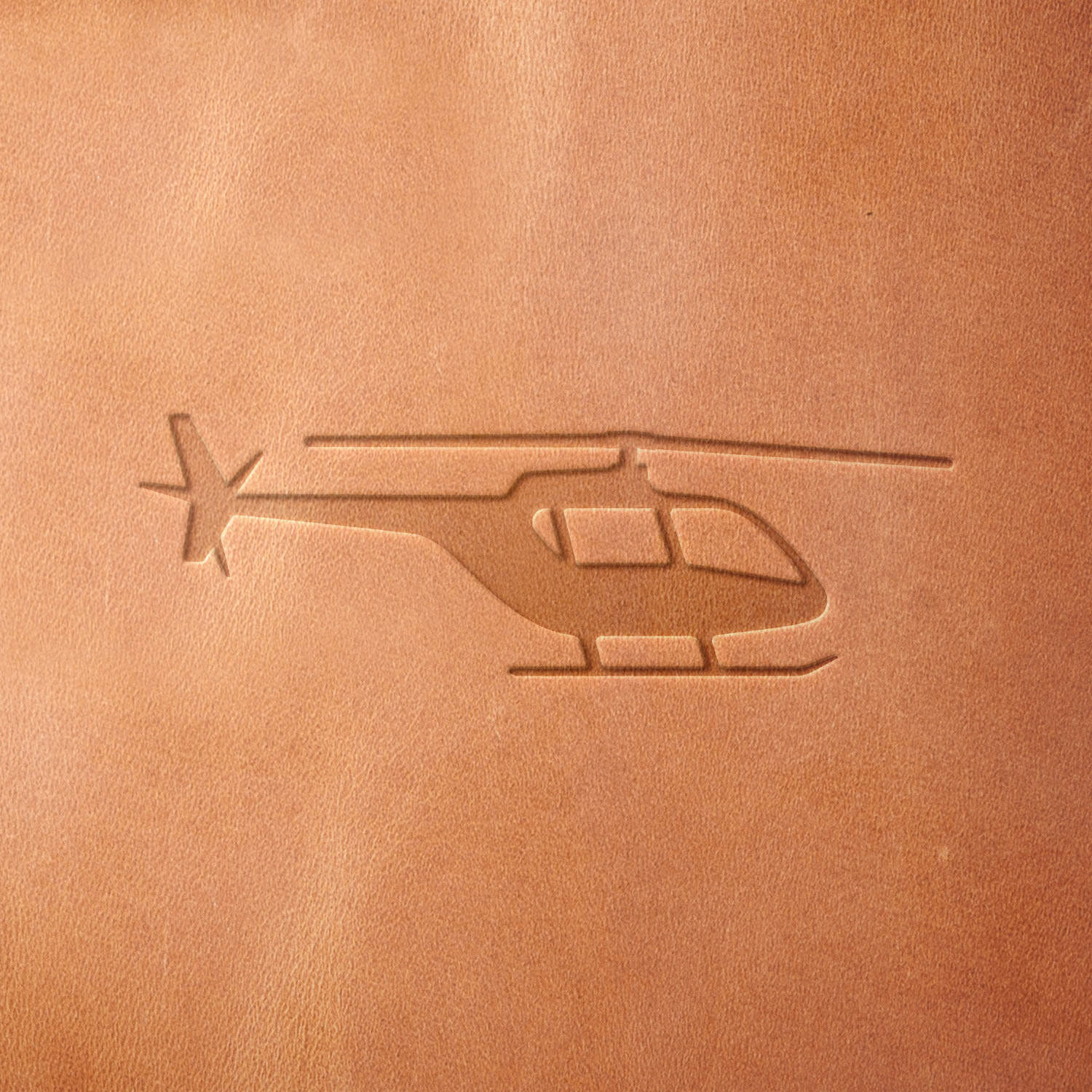Leather piece stamped with a Delrin leather stamp of a light civilian helicopter—perfect for flight log covers, air tour souvenirs, or gifts for rotorcraft enthusiasts.
