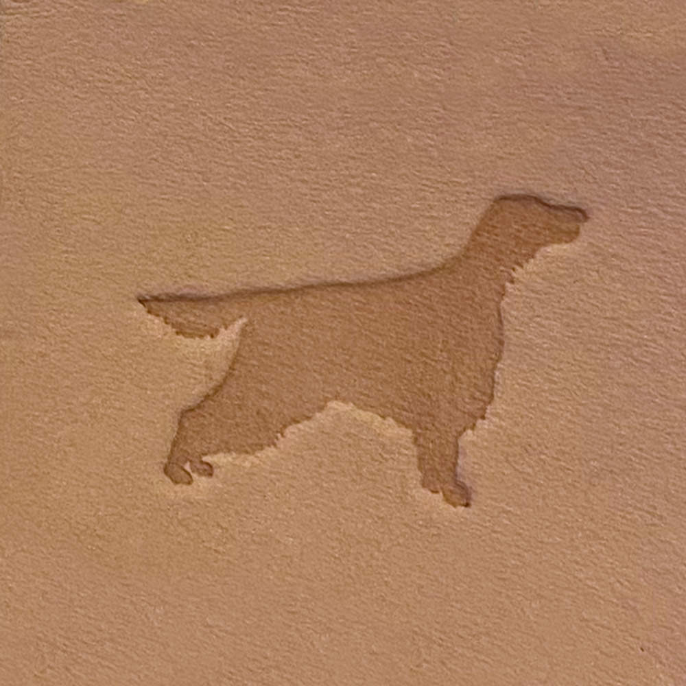 An image of a dog's silhouette on the Irish Setter Dog Delrin Leather Stamp, showcasing a beautifully defined dog in a standing position with its head, body, tail, and legs clearly depicted. The background is a uniform brownish-beige color.