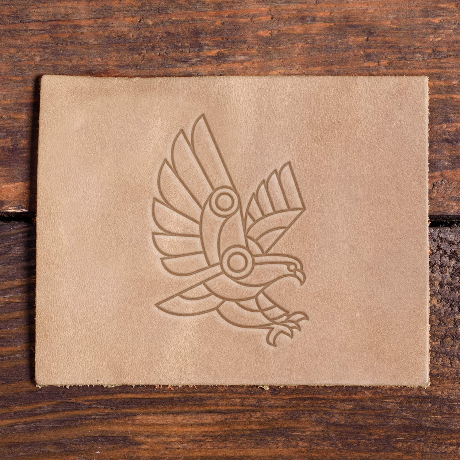 Stamped impression of a geometric bird in flight made with a Delrin leather stamp on natural veg-tan leather.