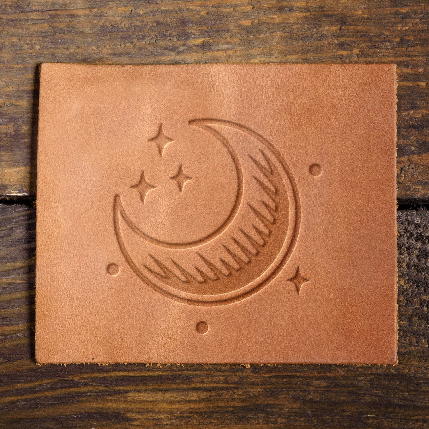 Leather sample featuring a stamped crescent moon and stars, creating a celestial impression on the surface.