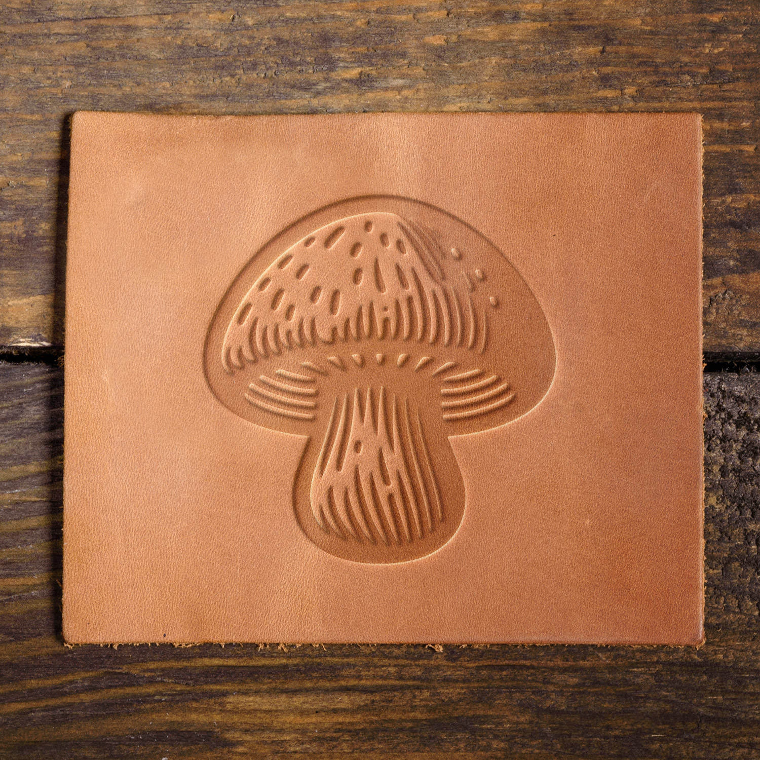 Leather sample featuring an embossed mushroom stamp, showcasing intricate details for a rustic touch.