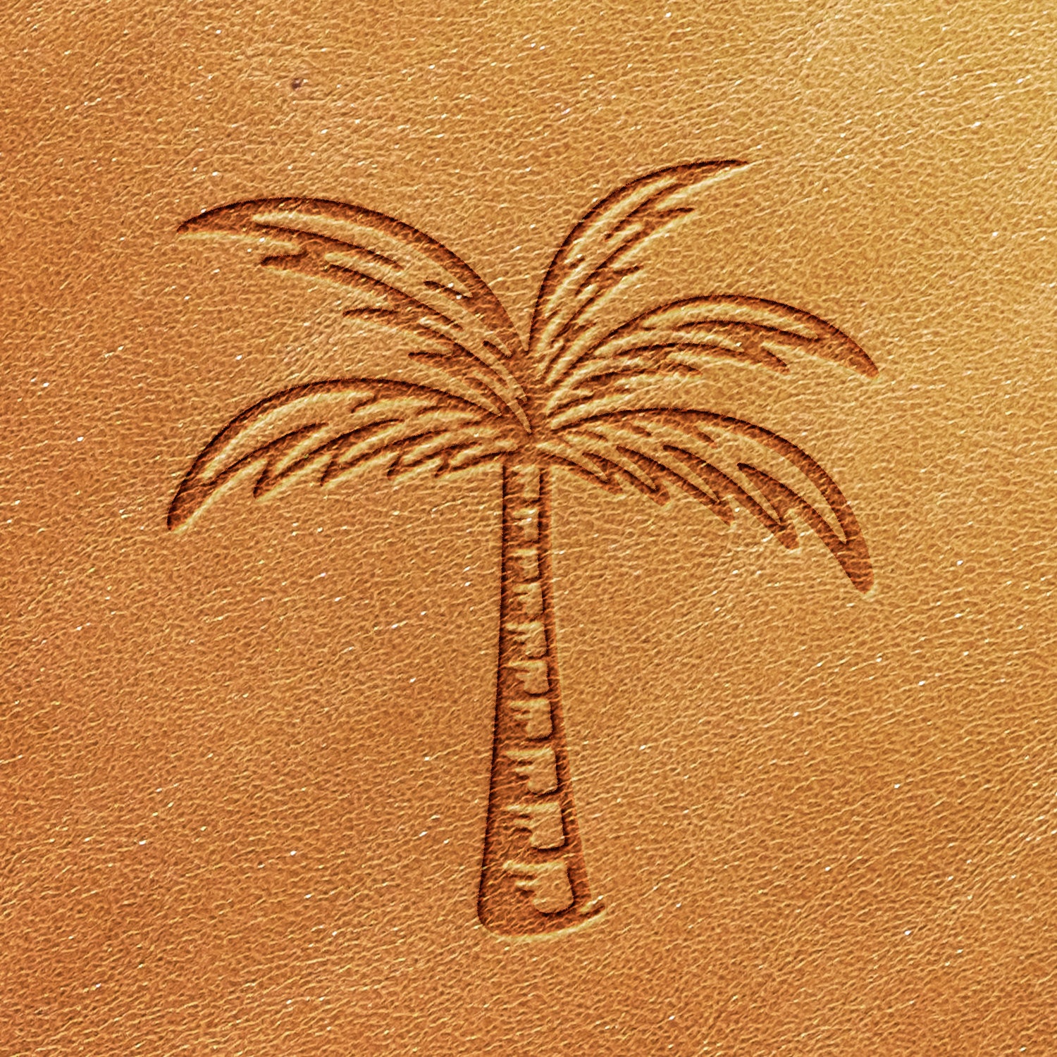 A close-up of an intricate design created using the Palm Tree Delrin Leather Stamp on light brown leather, showcasing the tree’s trunk and fronds in fine detail. The leather exhibits a smooth texture with visible grain.