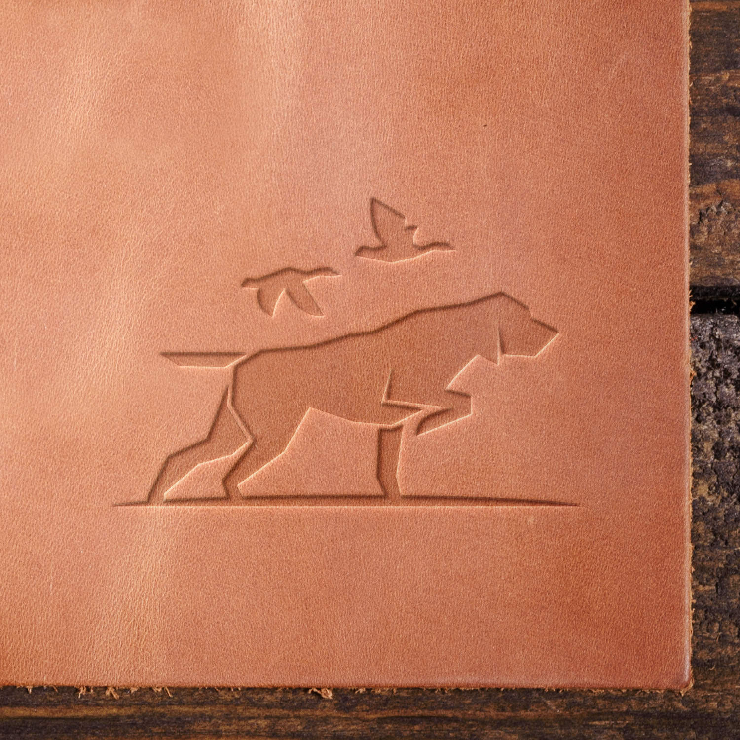 Leather sample showcasing a stamped hunting dog design using a delrin leather stamp, highlighting the sleek lines of the dog’s stance and the birds in flight.