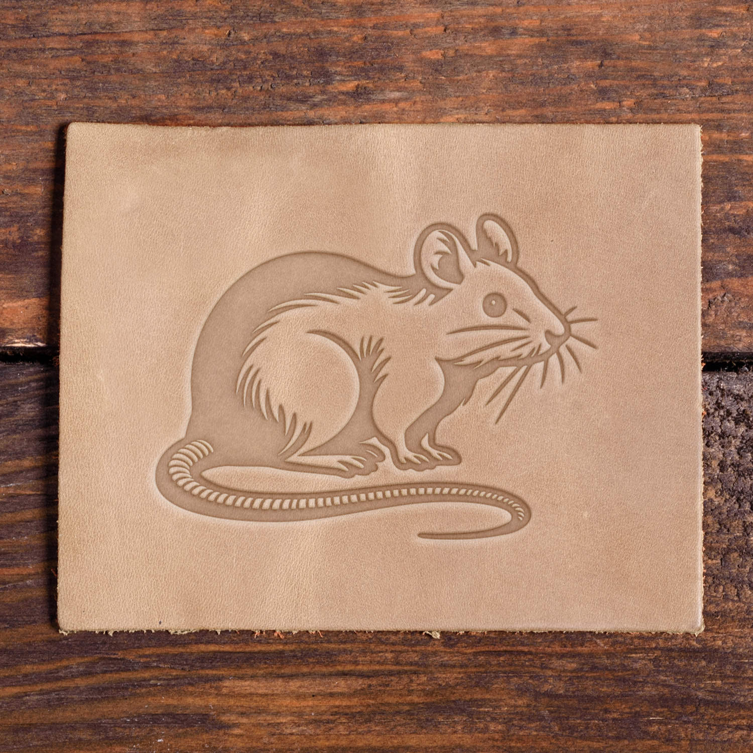 Mouse design stamped into leather using a Delrin stamp, shown on a wooden surface.