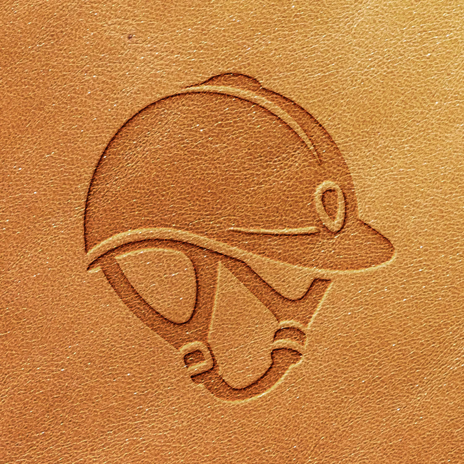 Embossed image of a jockey helmet using the Riding Helmet Delrin Leather Stamp on a light brown leather surface.