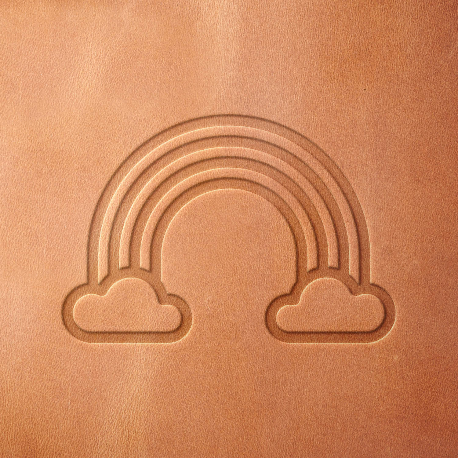 Leather sample showcasing a stamped rainbow design using a delrin leather stamp, emphasizing the curved arcs and soft cloud shapes.