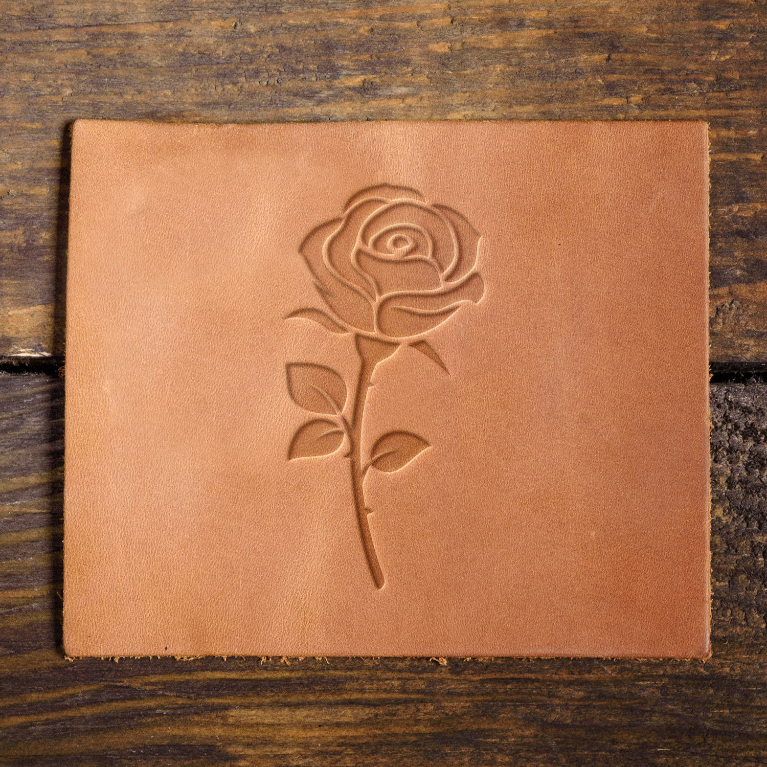 Leather sample showcasing a rose stamped with a Delrin leather stamp, highlighting the intricate petal details and classic floral design.