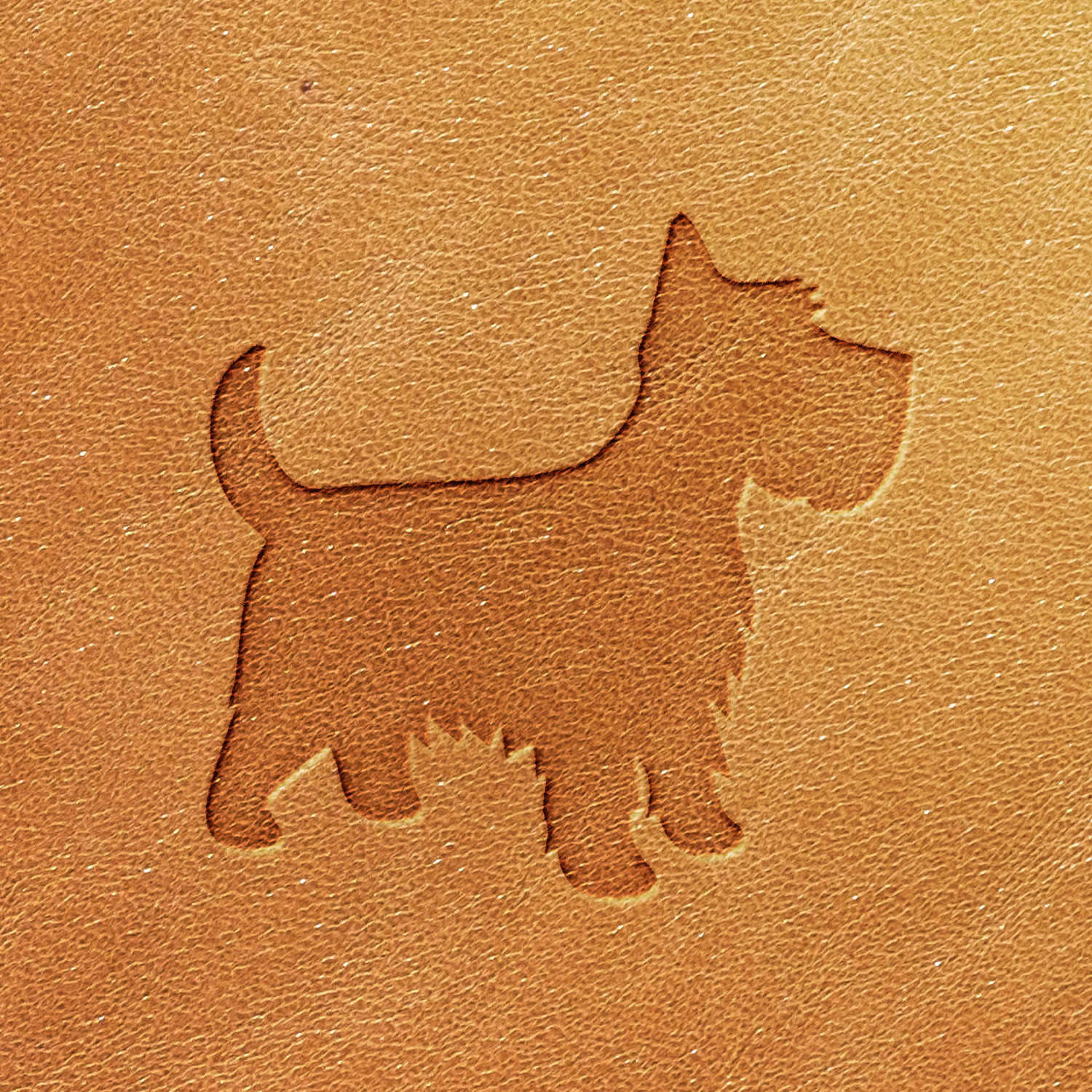 A Scottish Terrier Dog Delrin Leather Stamp embosses the impression of a small dog with pointed ears, a bushy tail, and a short stature onto light brown leather. The background features a textured, natural leather surface.