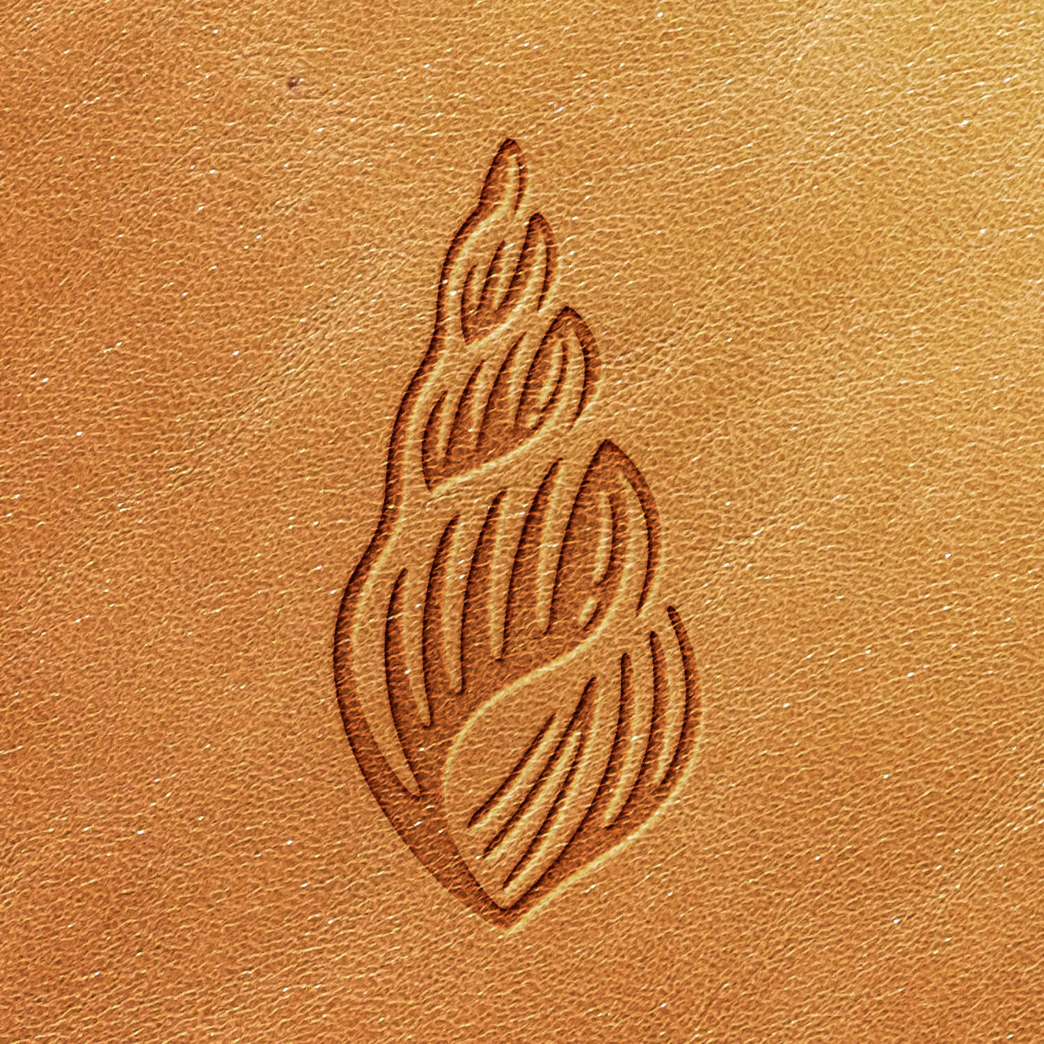 A close-up view of an embossed seashell design on a textured, light brown leather surface. The seashell has a spiraling pattern and appears to be neatly engraved into the leather using the Seashell Delrin Leather Stamp.