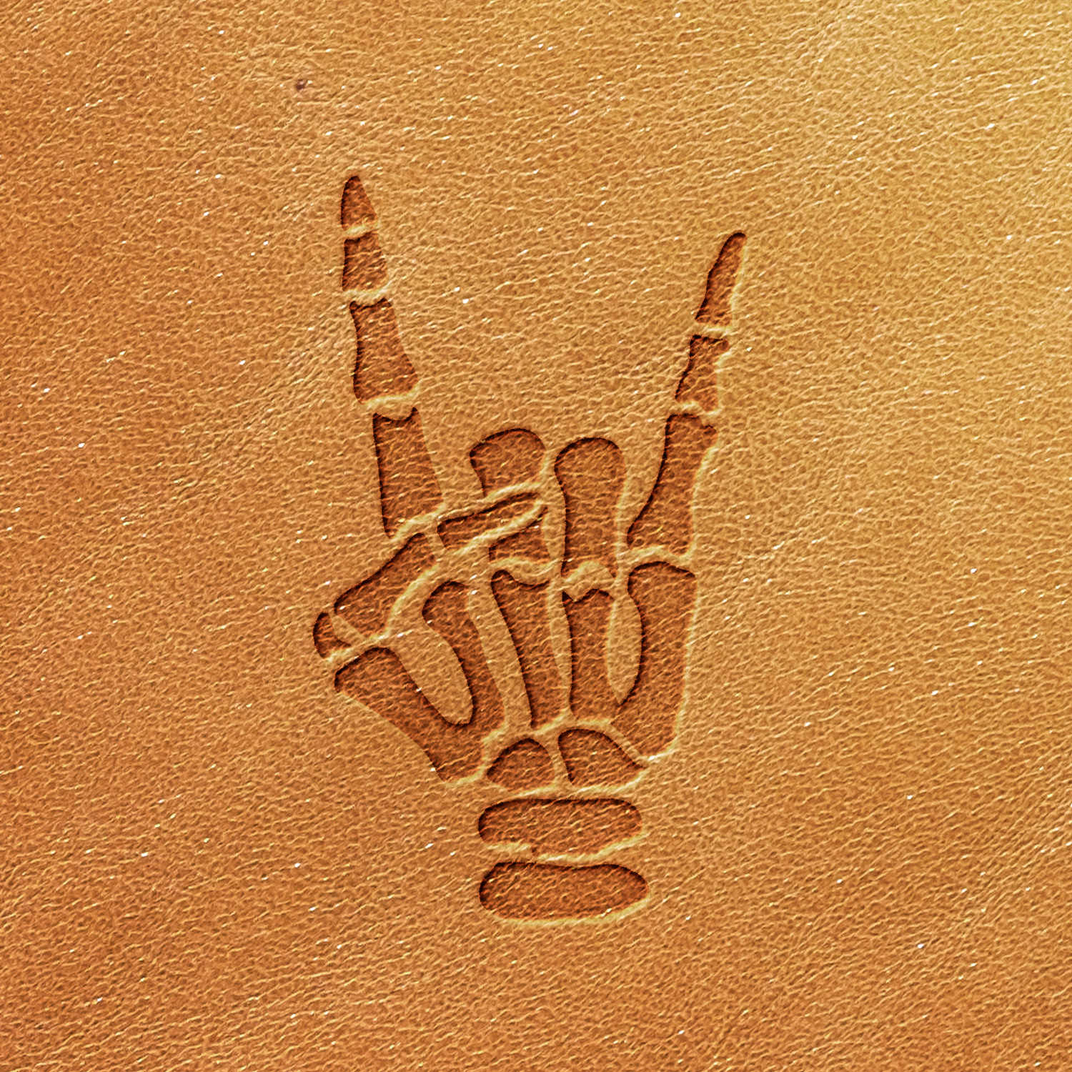 The Skeleton Hand Delrin Leather Stamp features a stylized skeletal hand embossed on a brown leather surface, with the index and pinky fingers extended upward while the thumb holds down the middle and ring fingers, forming the iconic "rock and roll" hand gesture.