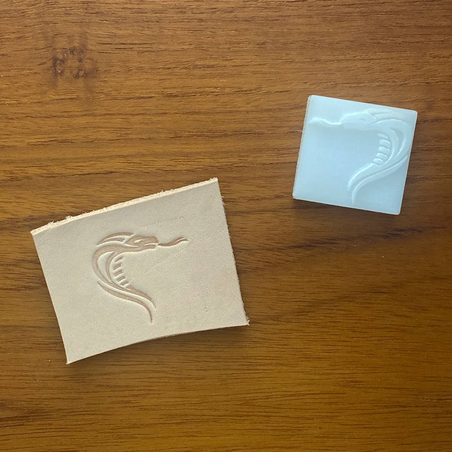 Vegetable-tanned leather stamped with a snake head design using a Delrin leather stamp, shown with the stamp.