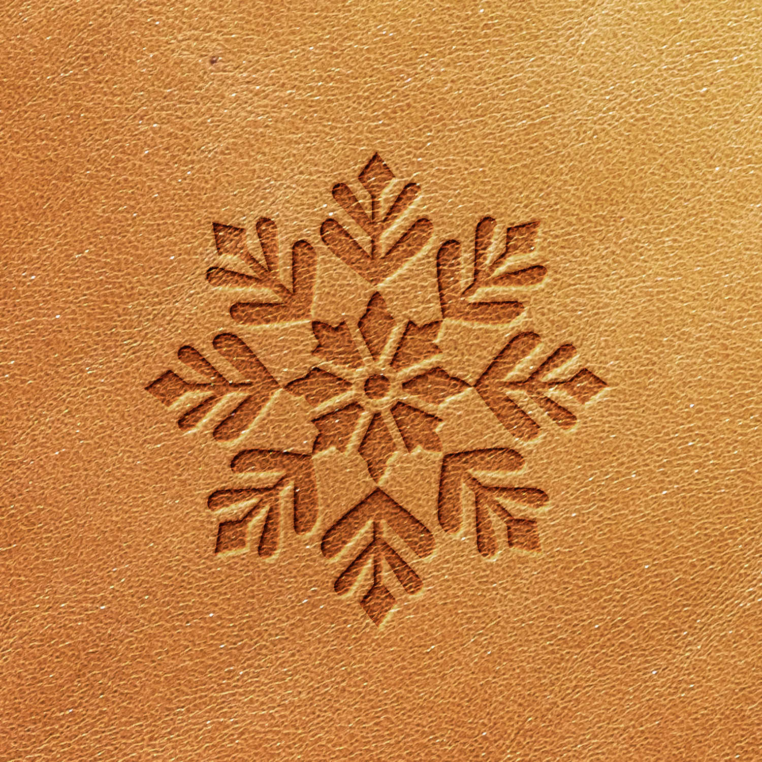 The Snowflake Delrin Leather Stamp creates a detailed geometric snowflake design on light brown leather, featuring six distinct branches with unique patterns. The texture of the leather remains prominently visible around the beautifully carved area.